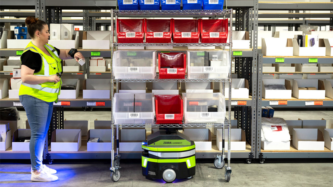 Press Release, Photography website, ODW Logistics, 16:9 Zebra Symmetry Fulfillment Picker in Aisle with Robot and Cart