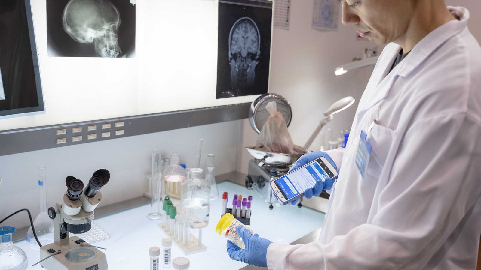 A healthcare worker uses a mobile computer with an integrated scanner to identify a sample container by scanning its label.