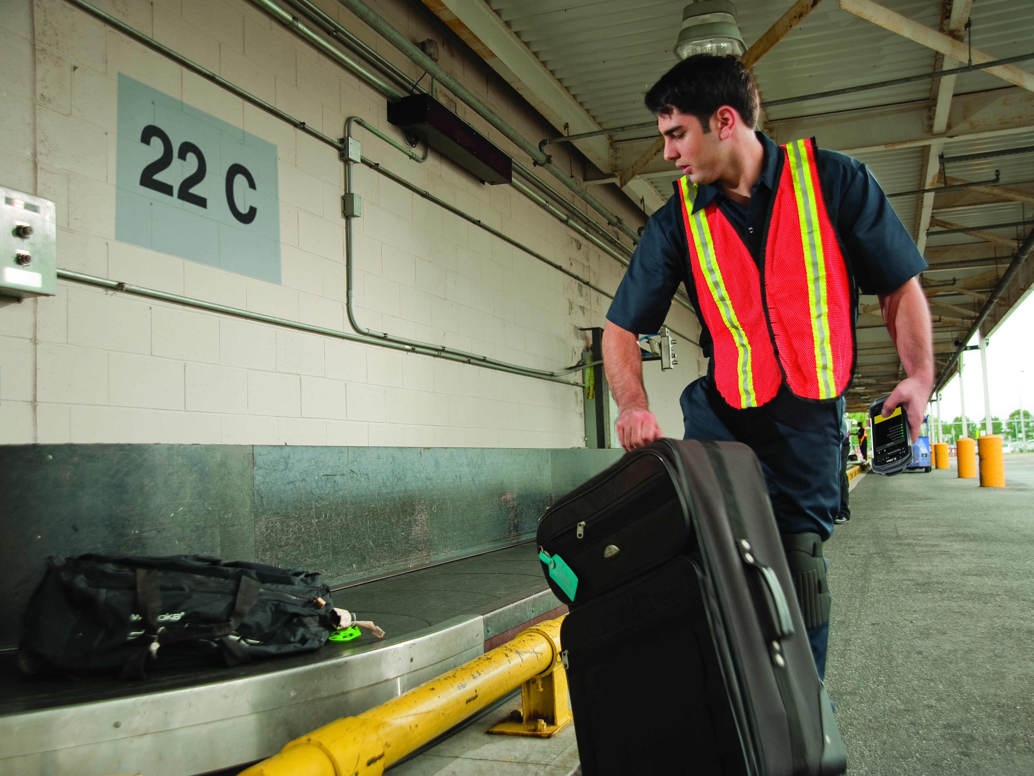 A baggage handler puts a bag on the conveyor belt