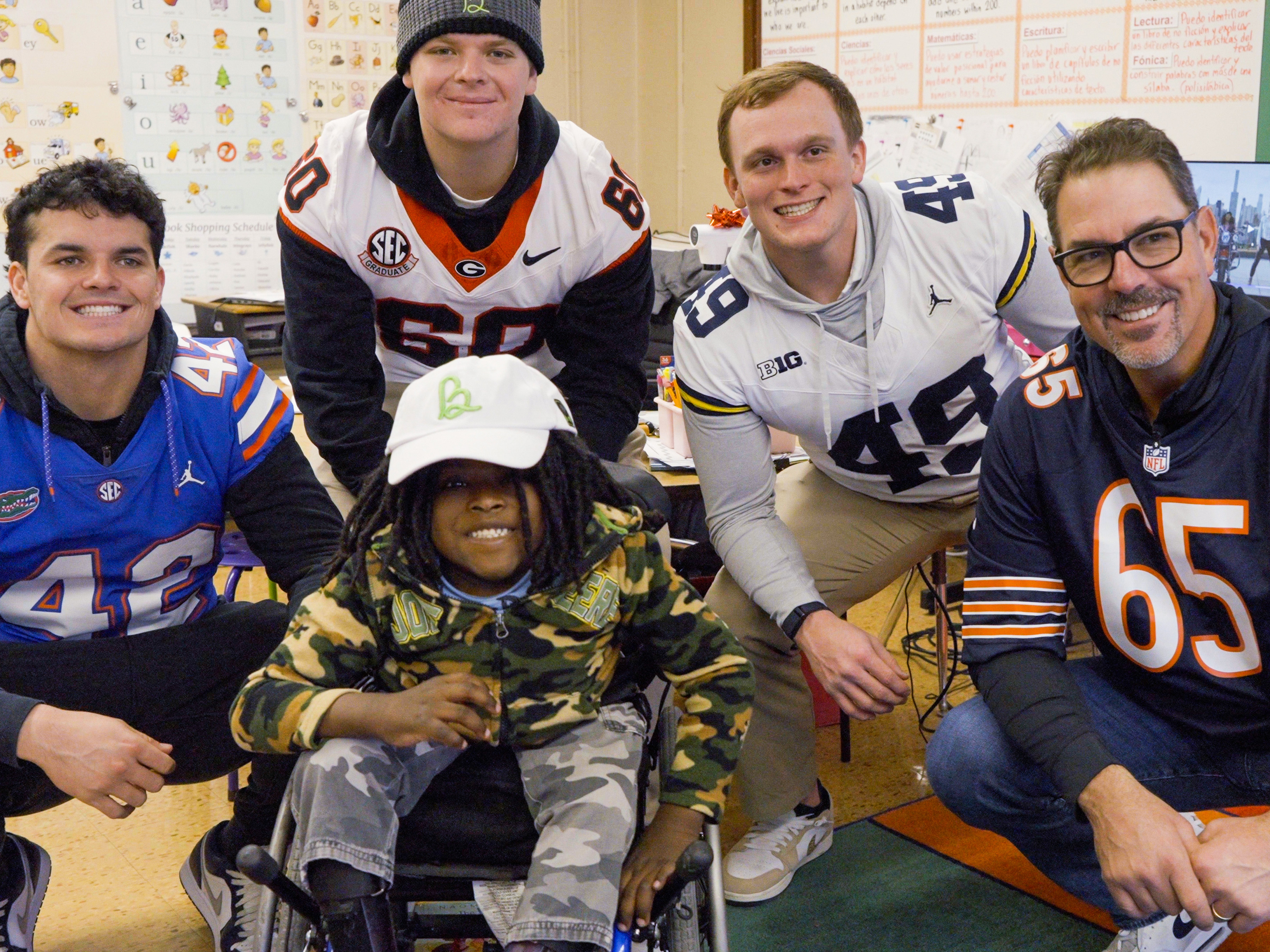 Group of football players posing with child