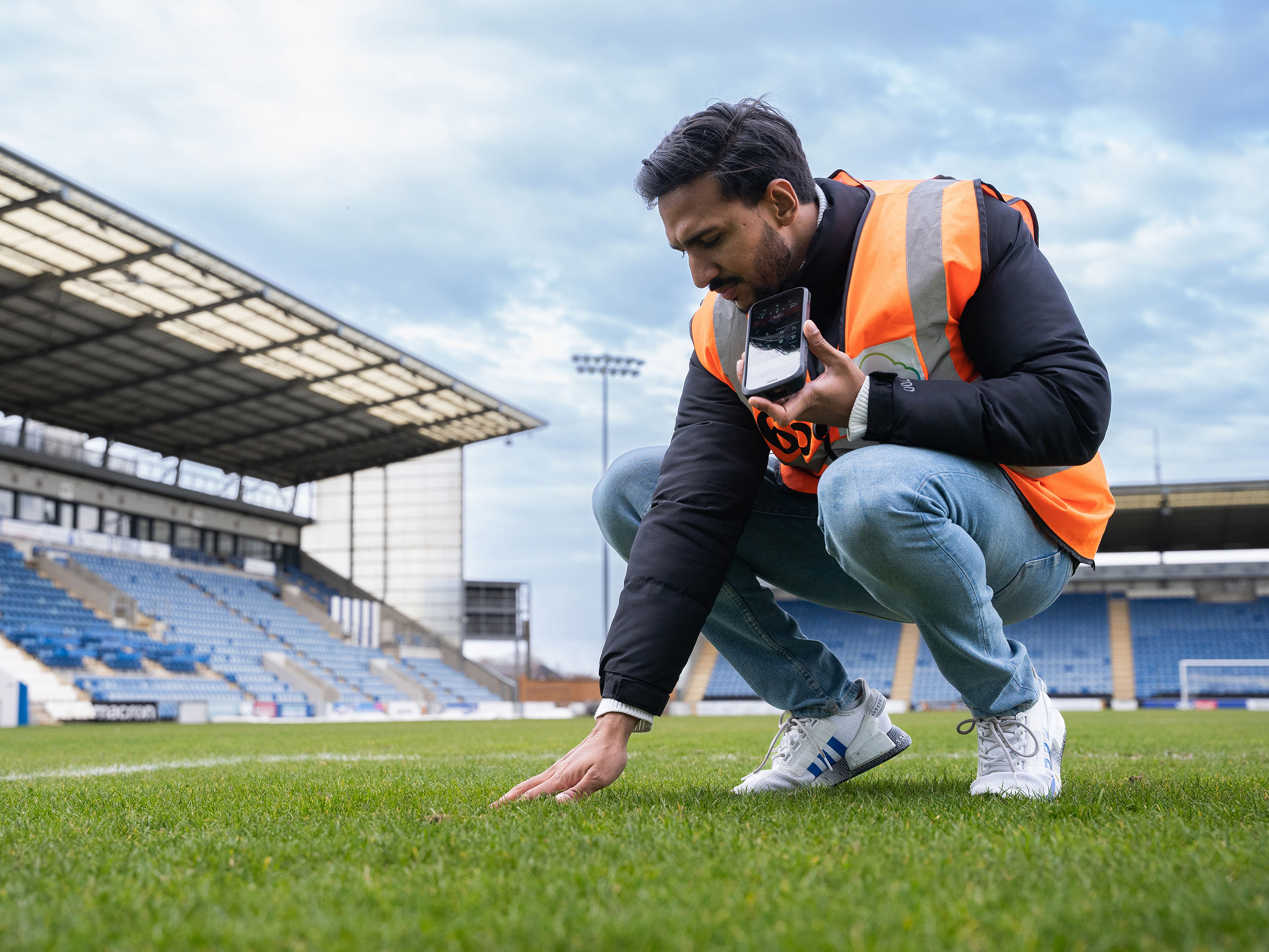 Man crouching on a football field touching grass