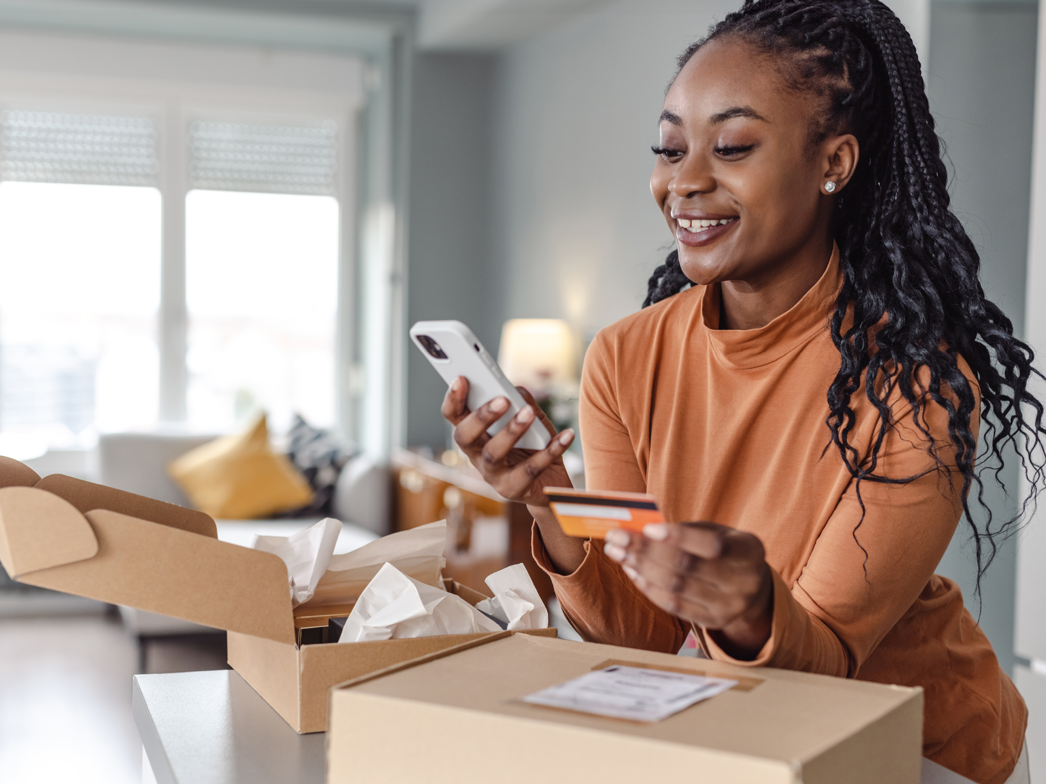 Woman holding a smartphone and looking at her credit card