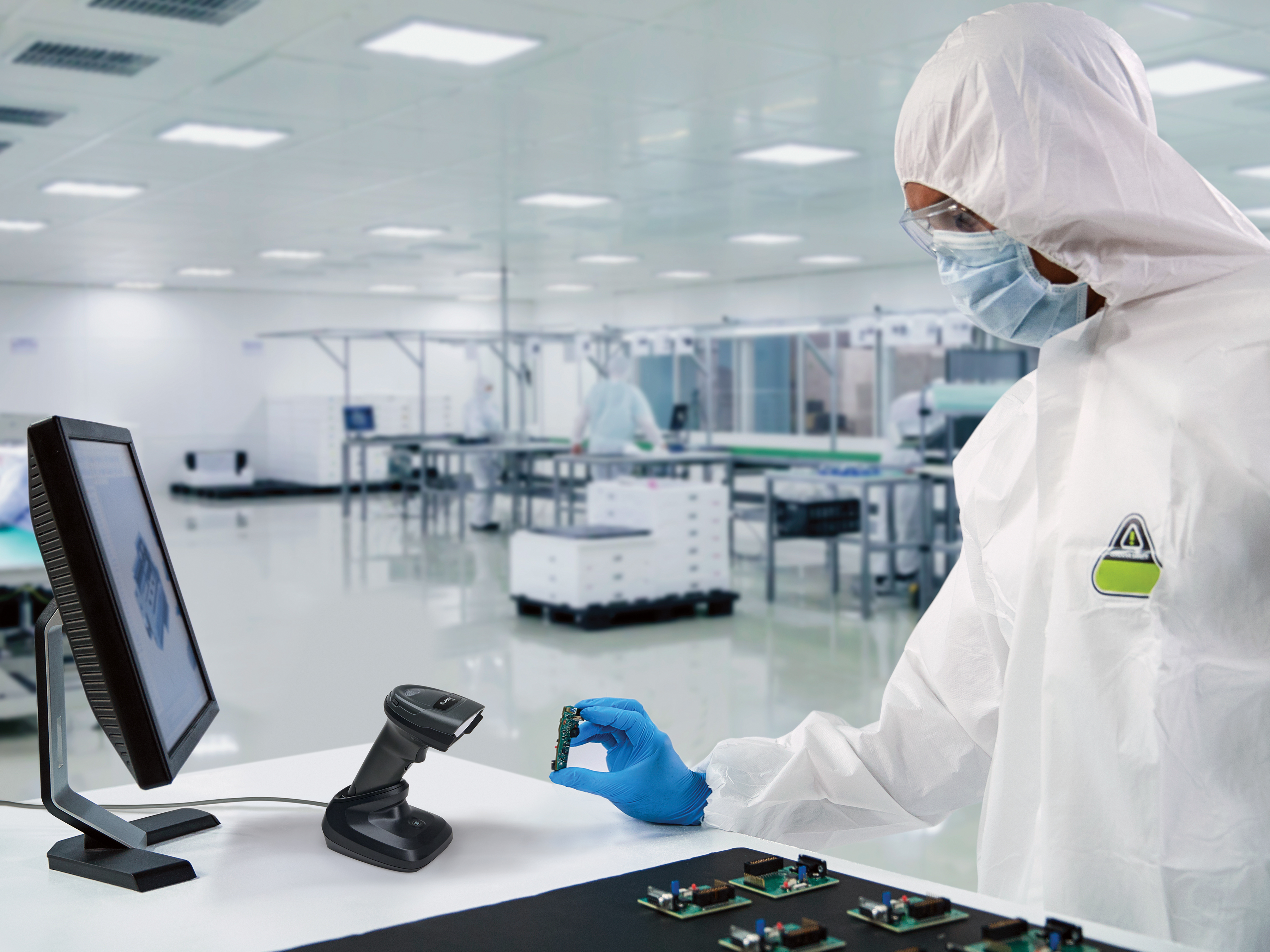 Worker using a Zebra hands-free scanner in a cleanroom environment. Worker using a Zebra hands-free scanner in a cleanroom environment.