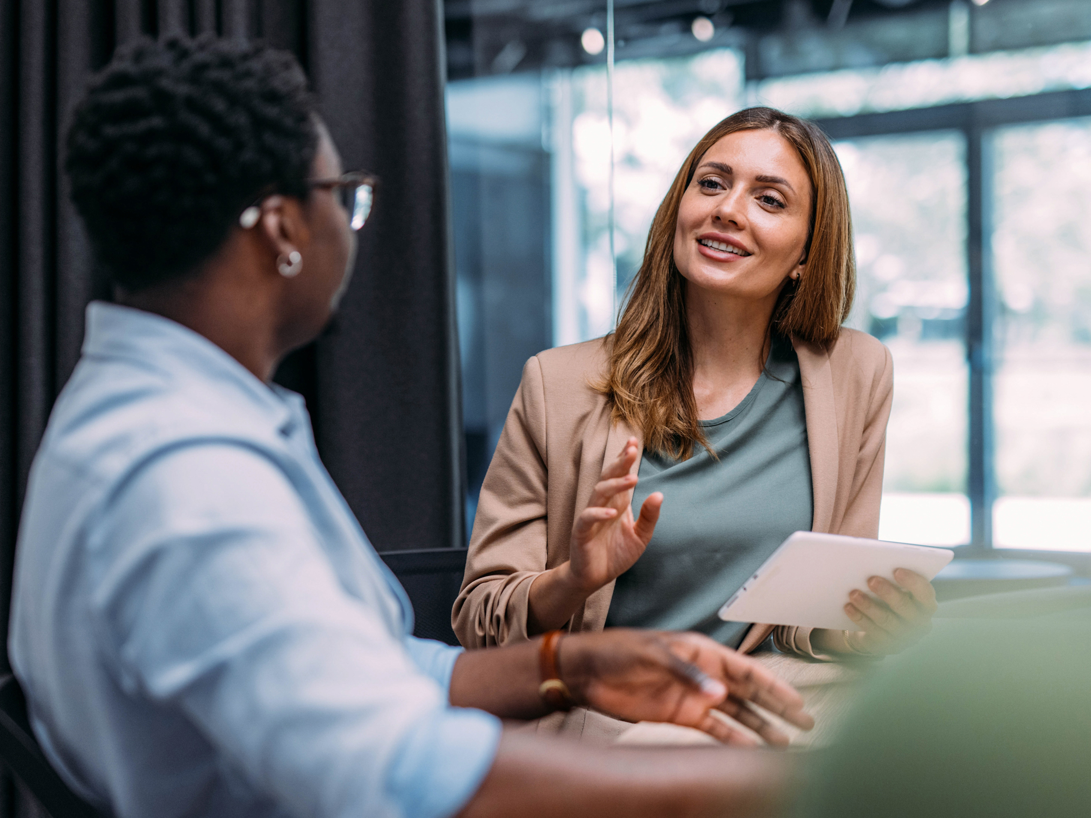 A female colleague holding a tablet while speaking to a male colleague A female colleague holding a tablet while speaking to a male colleague