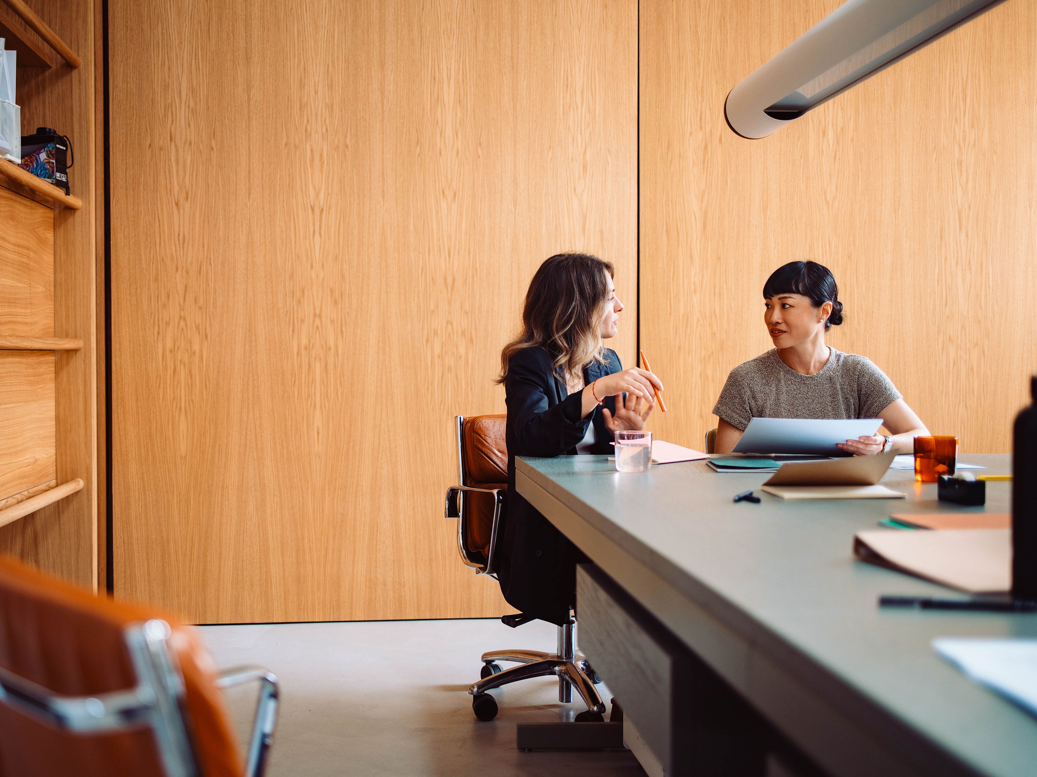 Two professionals collaborating in an office boardroom. Two professionals collaborating in an office boardroom.