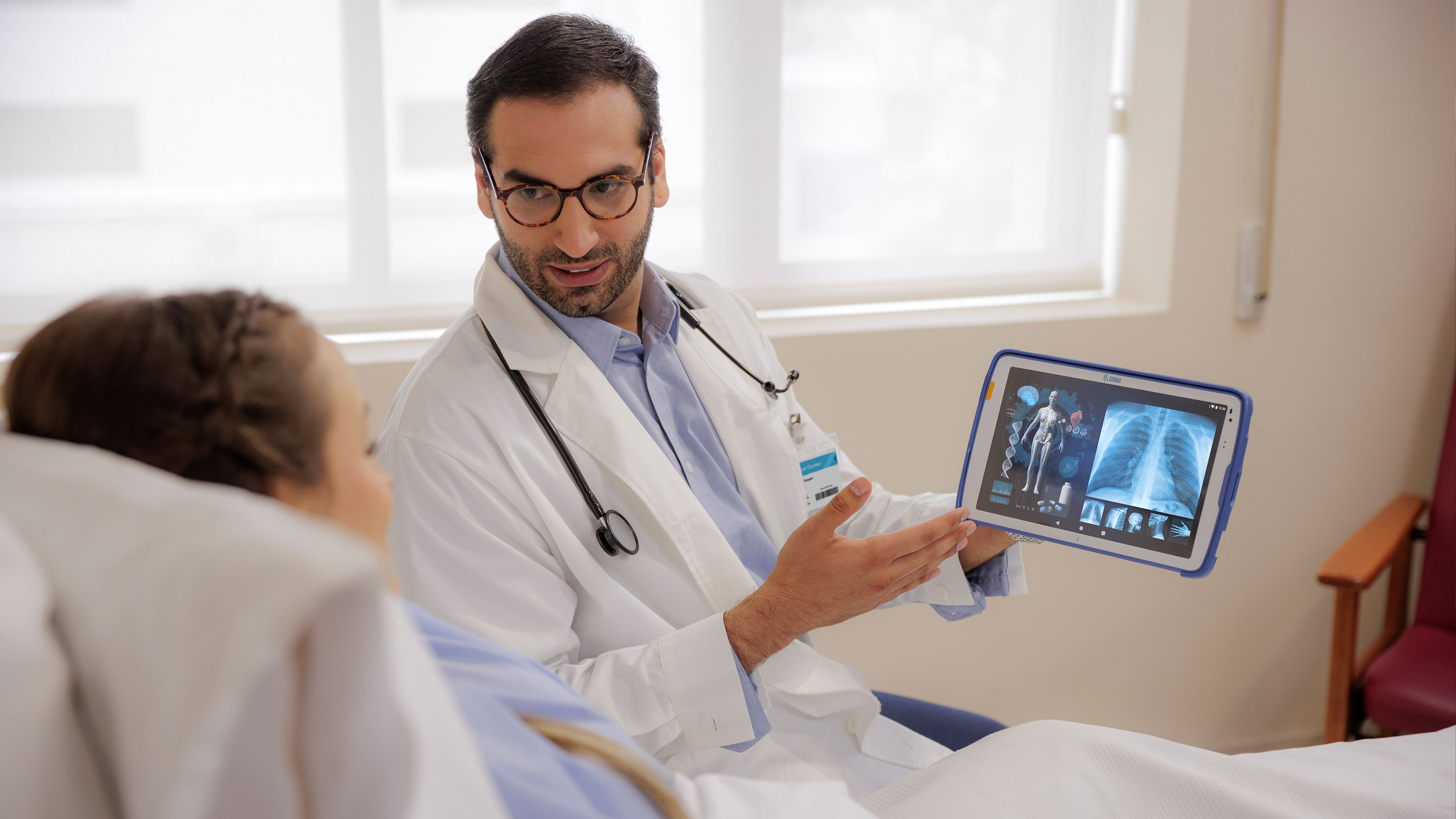 Doctor showing a patient information using a Zebra healthcare tablet. Doctor showing a patient information using a Zebra healthcare tablet.