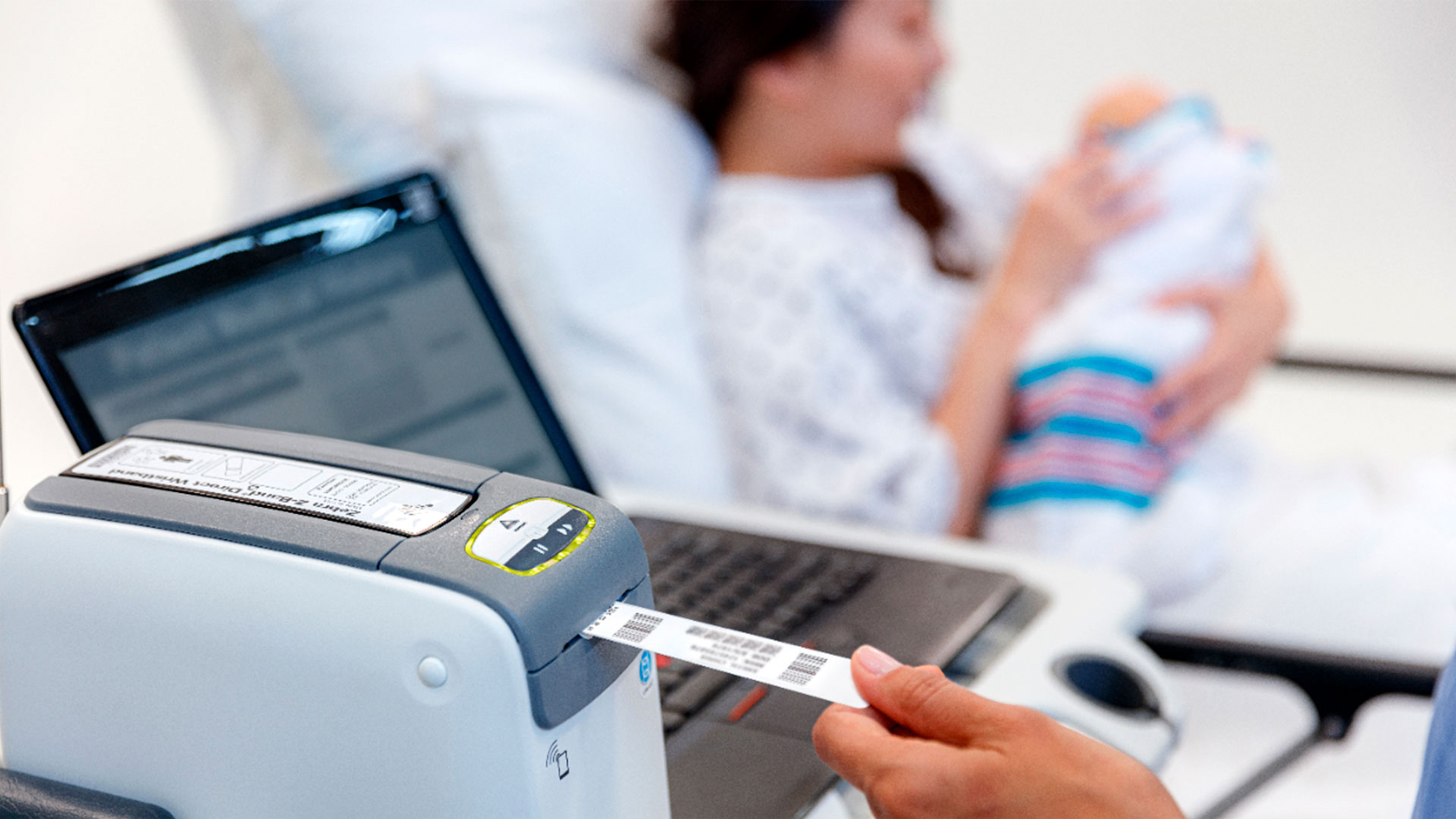Health professional using a Zebra desktop printer to label a patient wristband.  Health professional using a Zebra desktop printer to label a patient wristband.