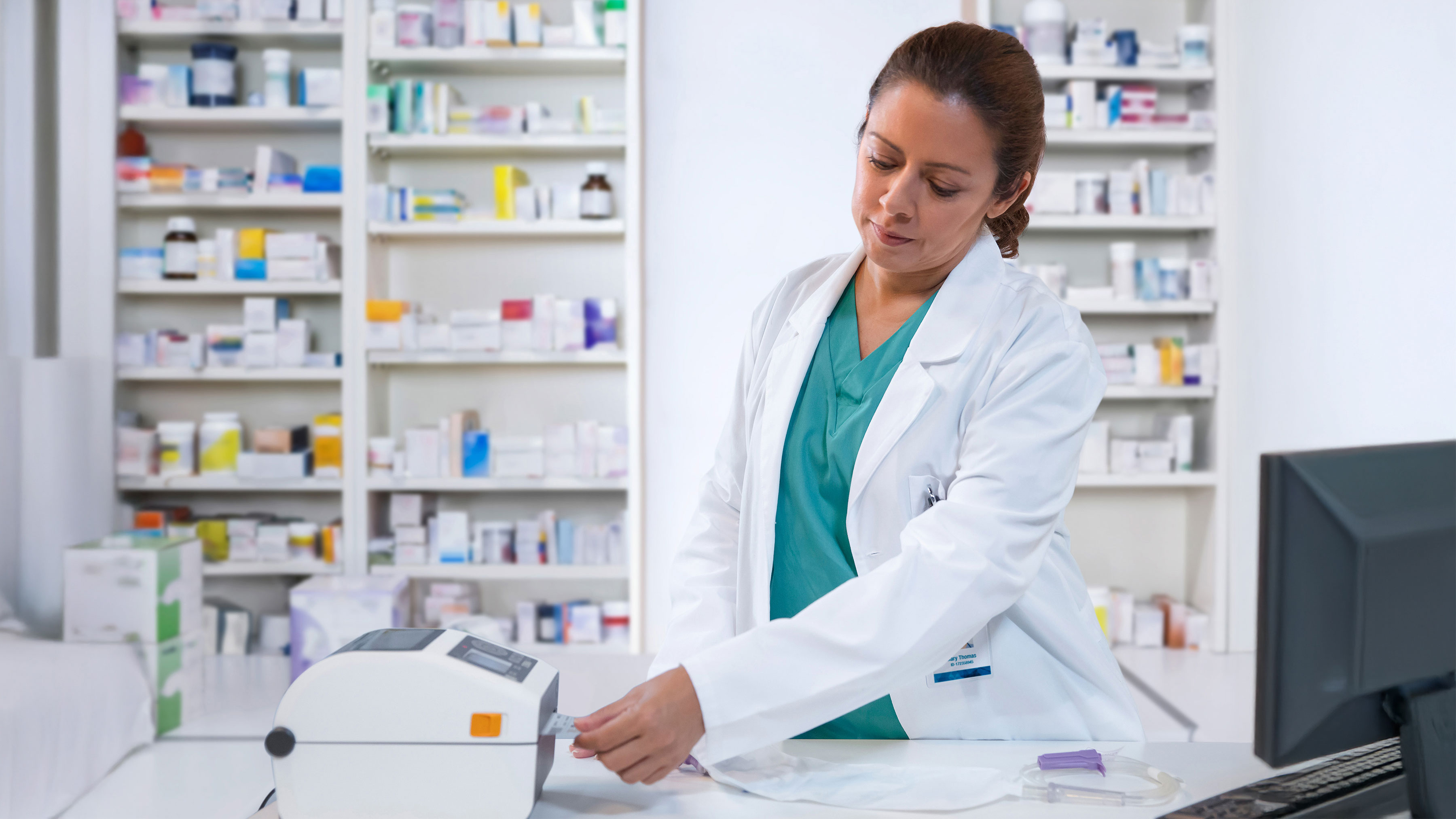 Pharmacist using a Zebra desktop healthcare printer to create a label. Pharmacist using a Zebra desktop healthcare printer to create a label.