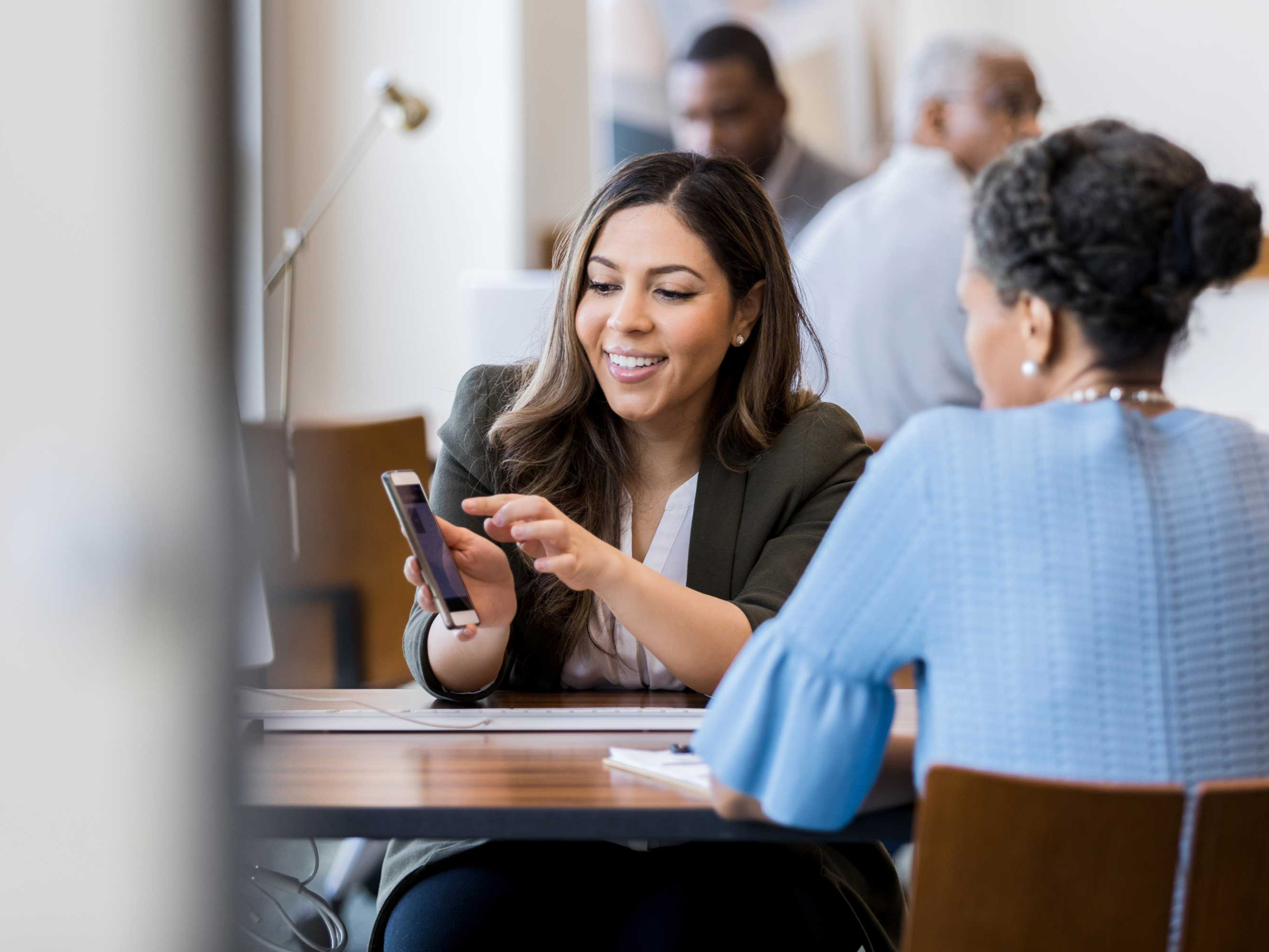 A colleague is showing their mobile computer to a co-worker in professional setting. A colleague is showing their mobile computer to a co-worker in professional setting.