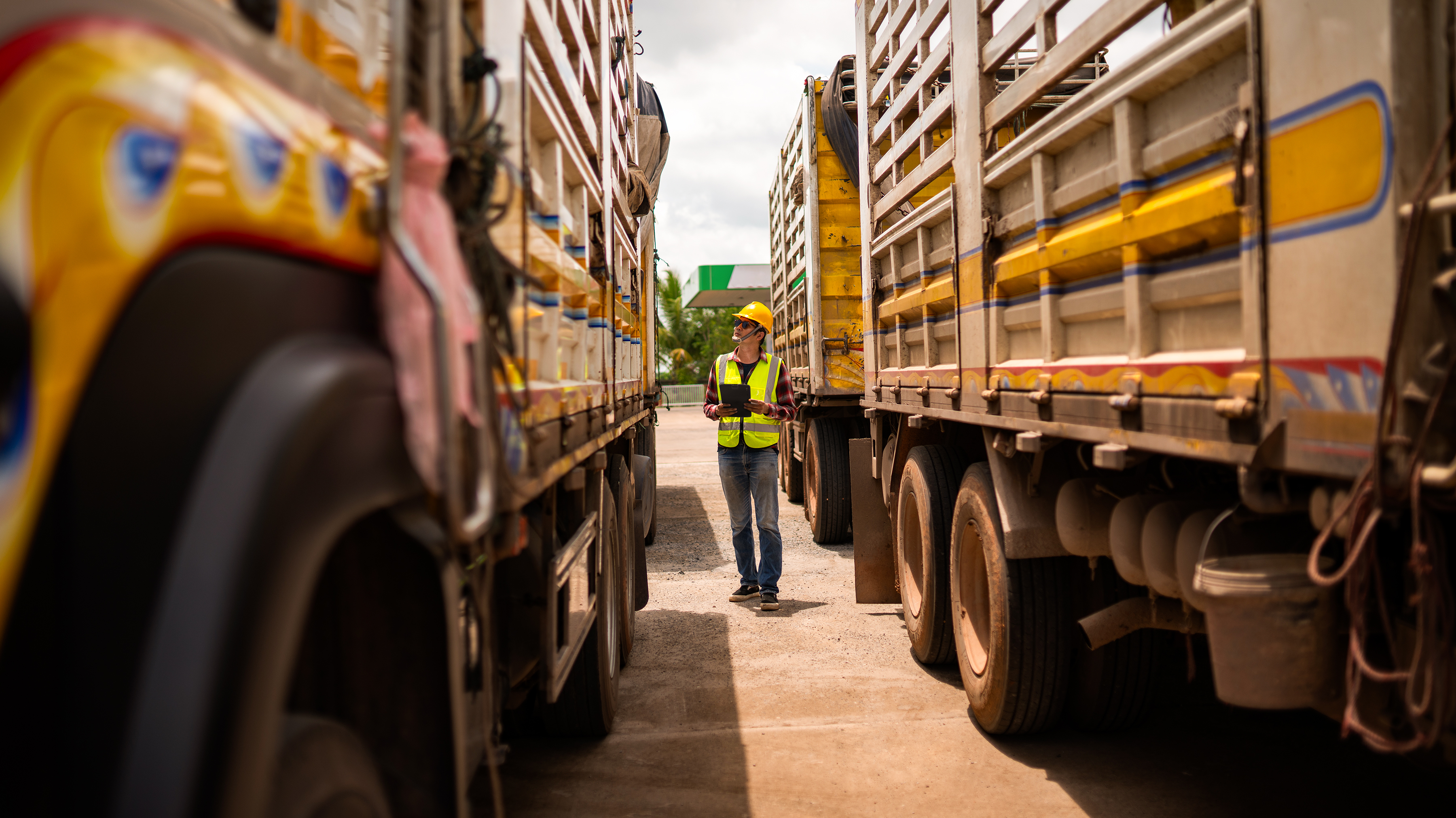 Logistics worker using a tablet in between two delivery trucks.  Logistics worker using a tablet in between two delivery trucks.