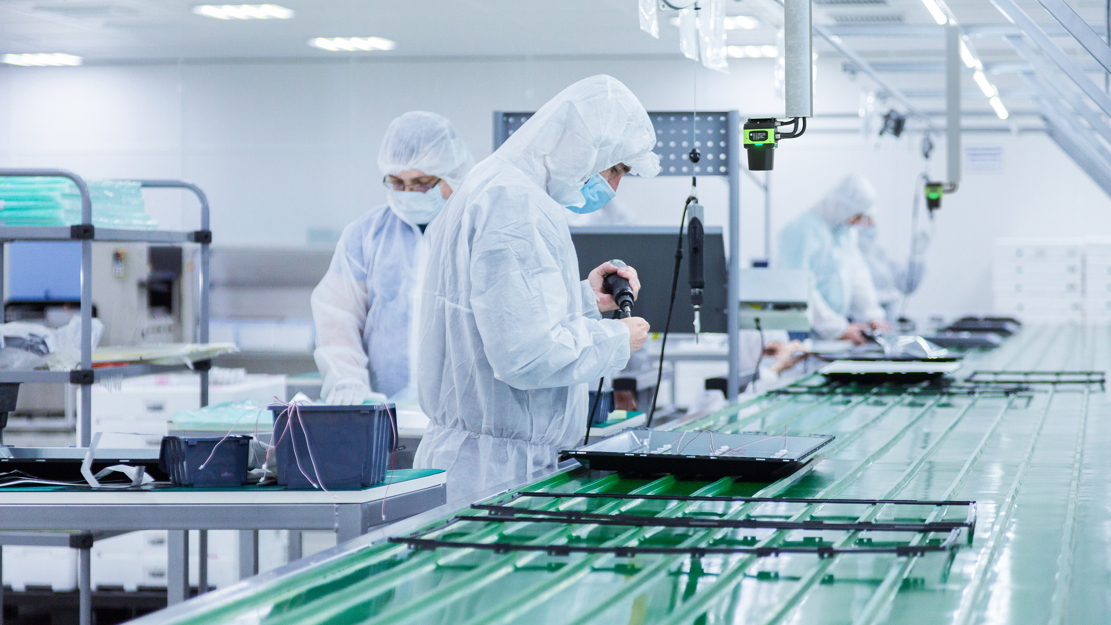 Cleanroom production operators at work wearing cleanroom suits Cleanroom production operators at work wearing cleanroom suits