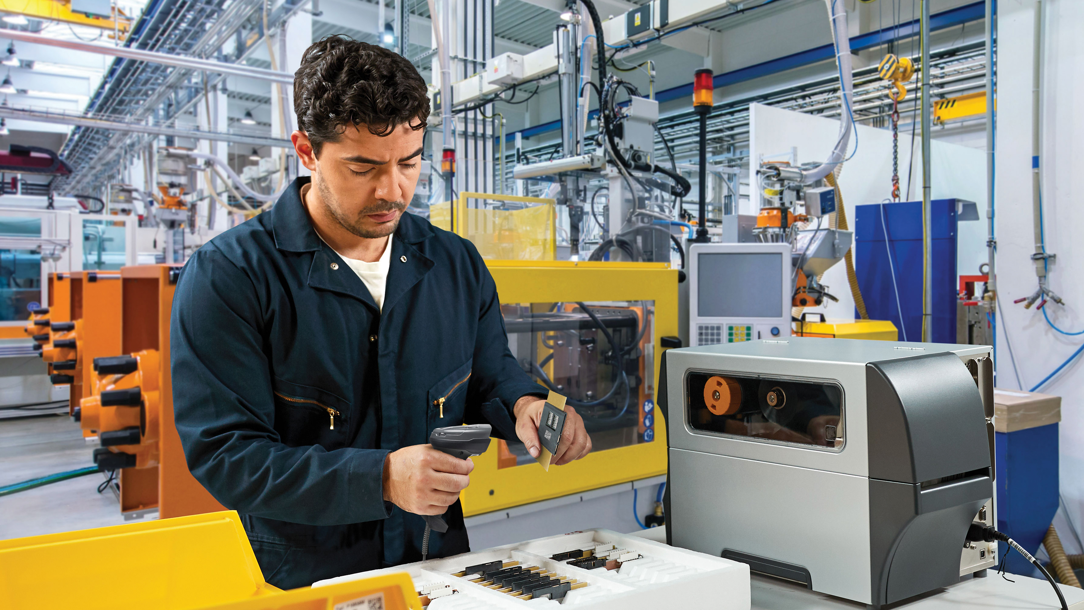 Worker using a Zebra handheld scanner in a manufacturing setting. Worker using a Zebra handheld scanner in a manufacturing setting.