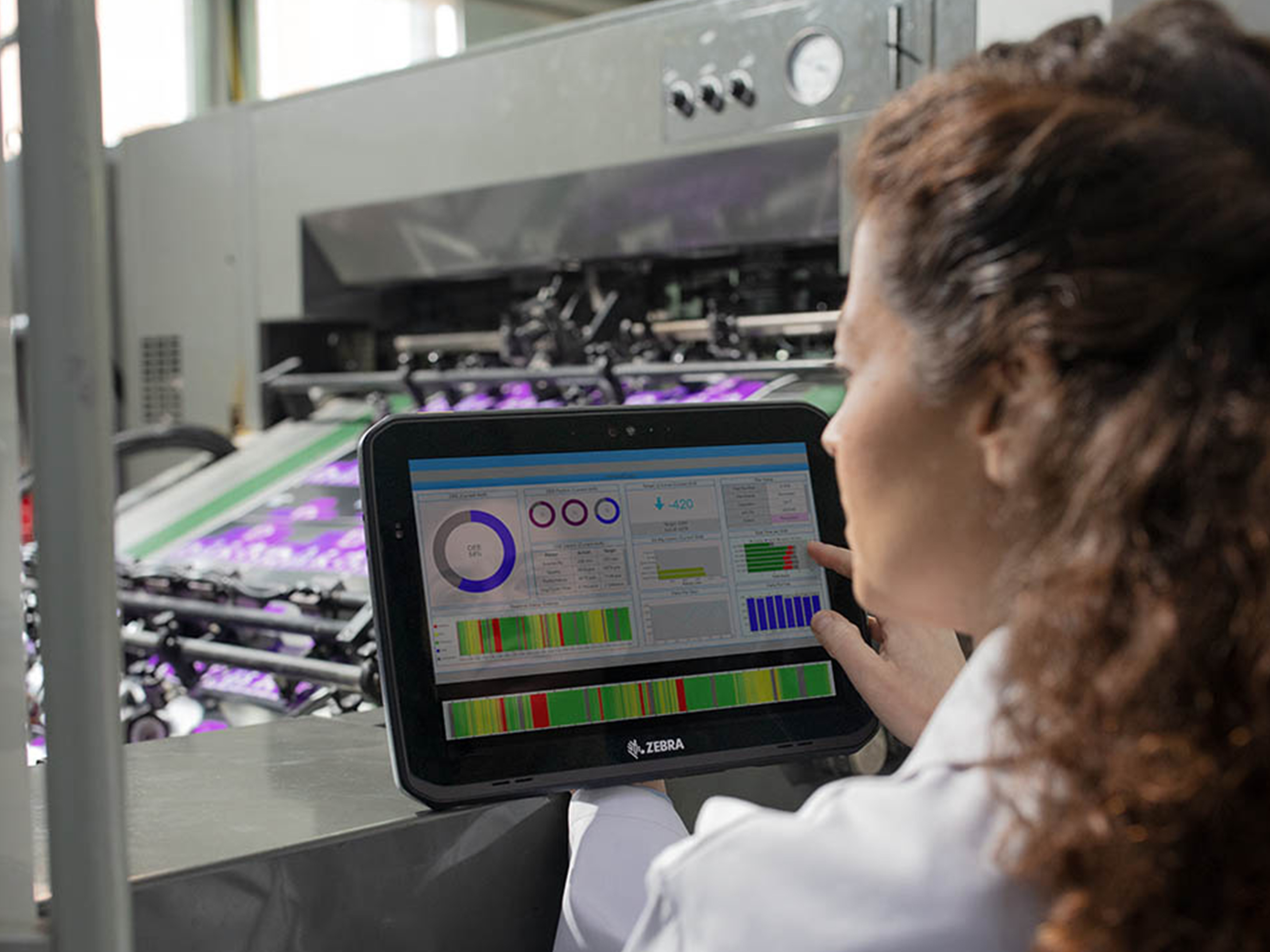 Manufacturing worker monitoring a machine using a Zebra tablet. Manufacturing worker monitoring a machine using a Zebra tablet.