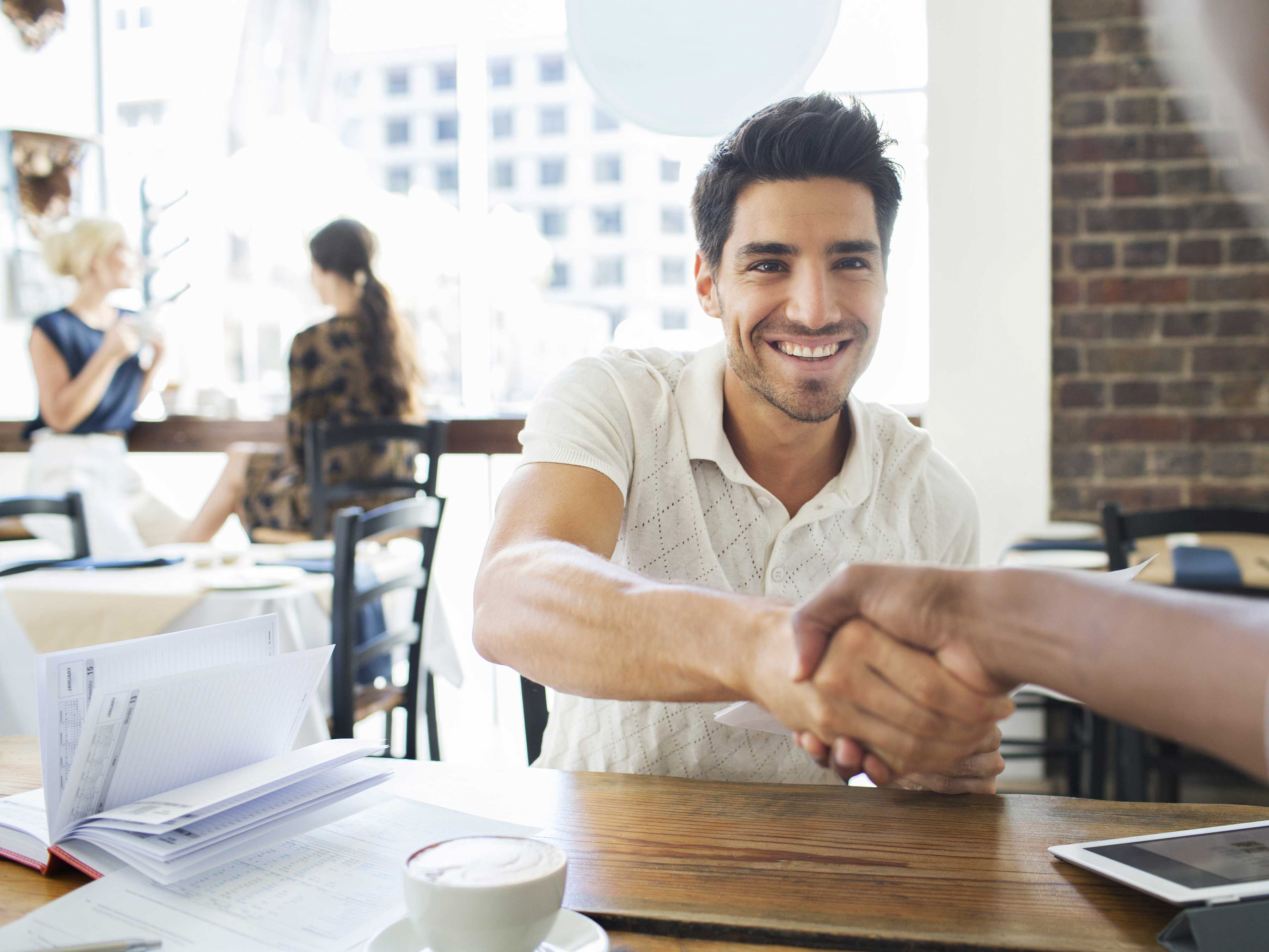 Two colleagues shaking hands in a cafe.  Two colleagues shaking hands in a cafe.
