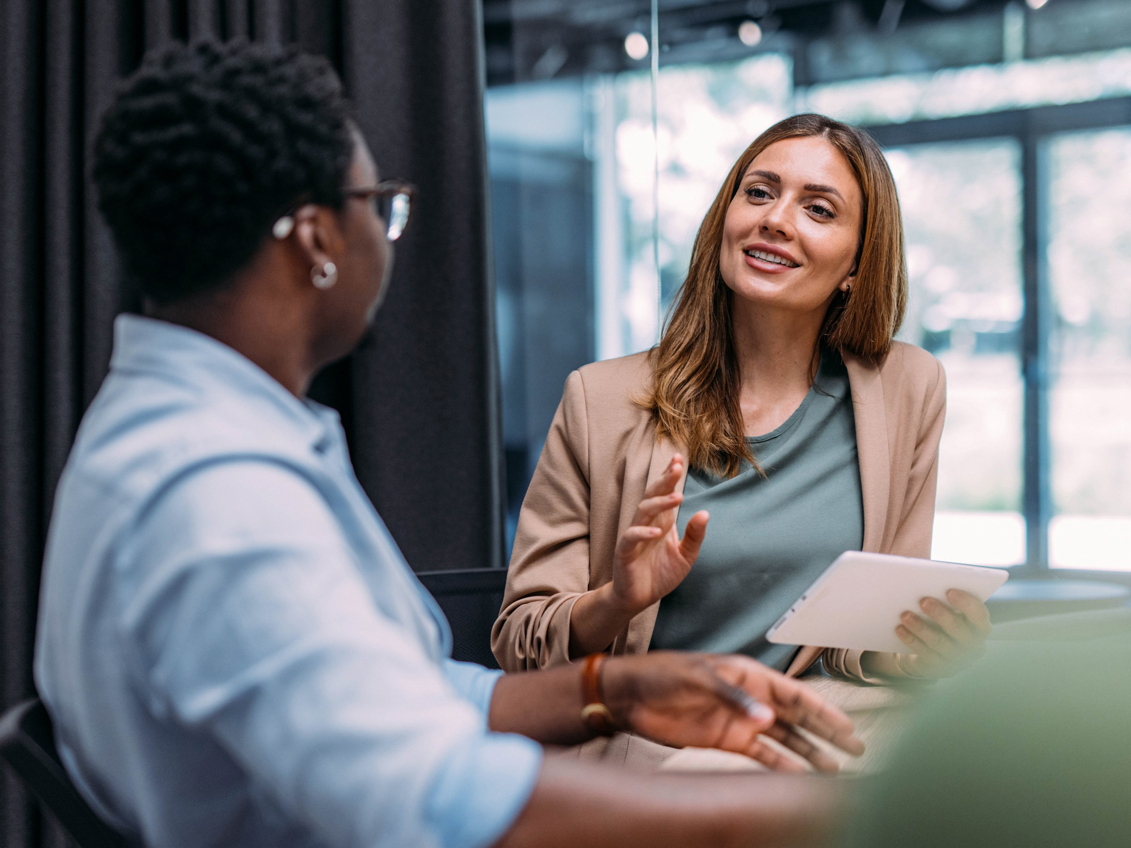 Female employee holding a white table while talking to a male colleague during a meeting Female employee holding a white table while talking to a male colleague during a meeting
