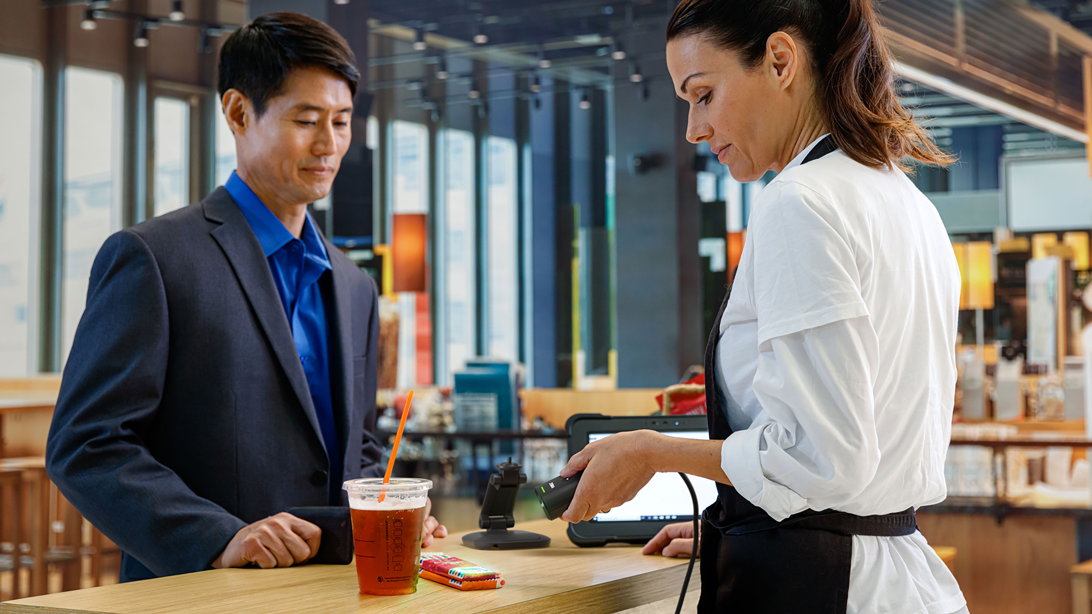 Customer at checkout with a retail employee scanning their purchase.