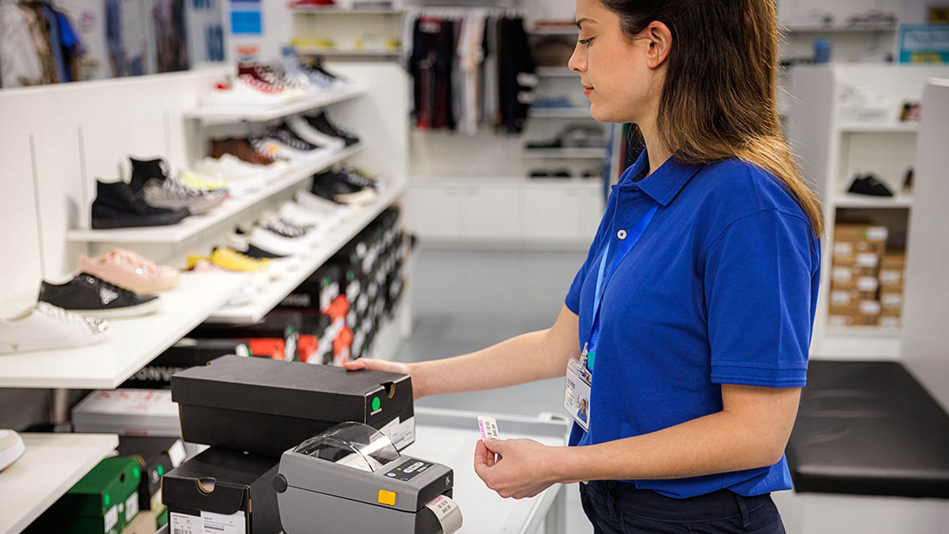 Retail employee using a Zebra desktop printer to create a label. Retail employee using a Zebra desktop printer to create a label.