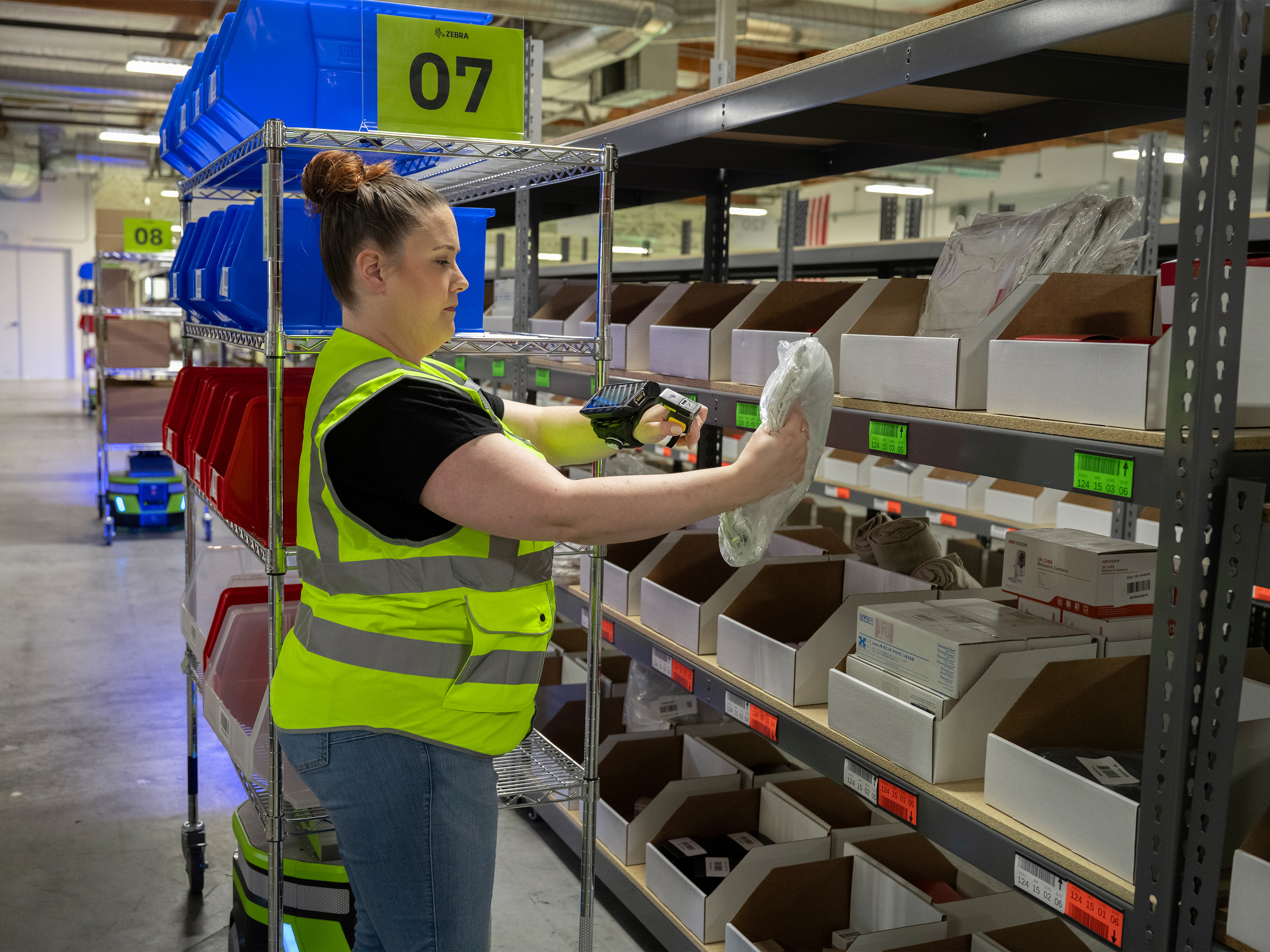Warehouse worker scanning an item with Zebra mobile robot next to her Warehouse worker scanning an item with Zebra mobile robot next to her