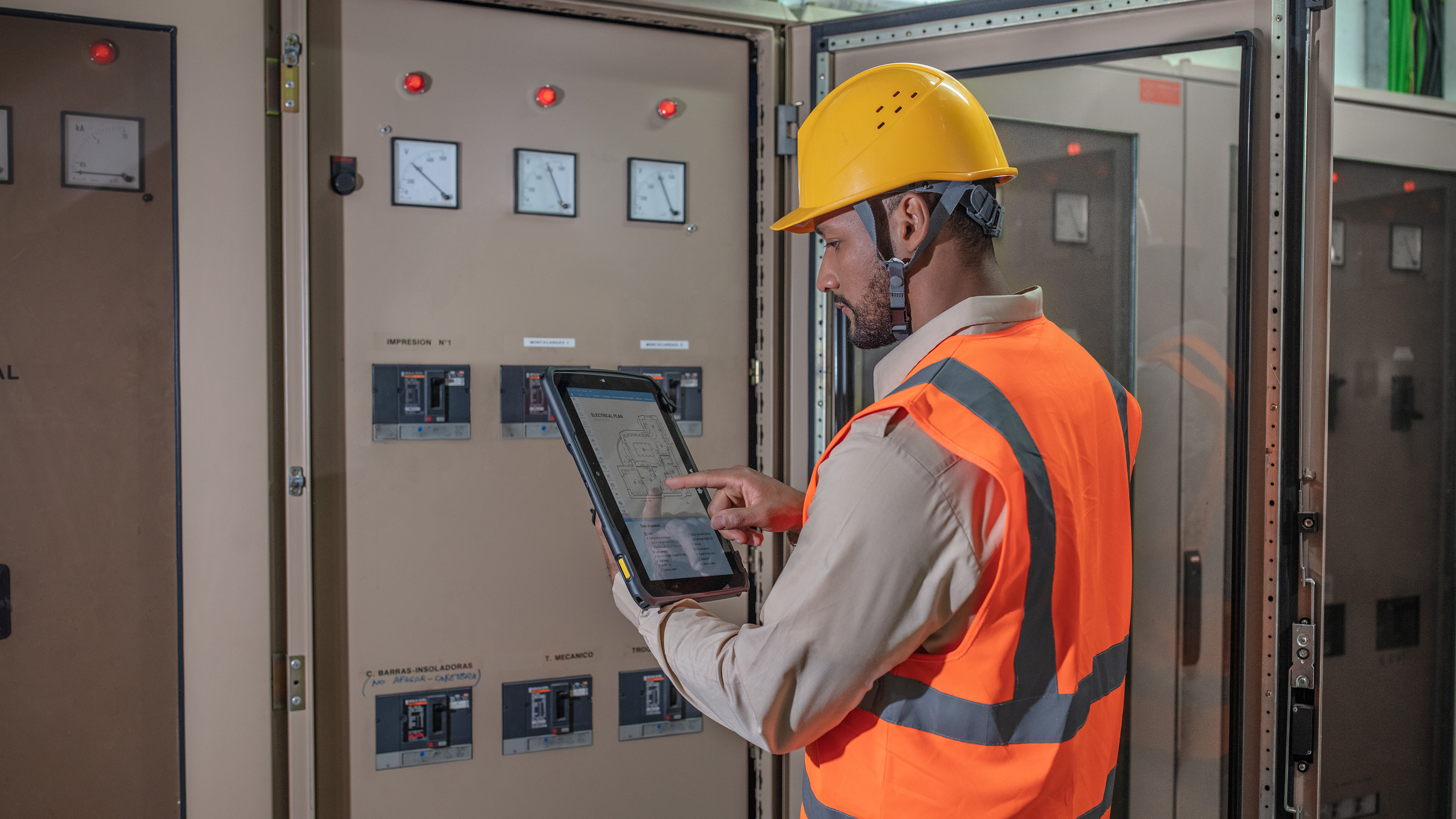 Technician working a control panel with a Zebra tablet. Technician working a control panel with a Zebra tablet.