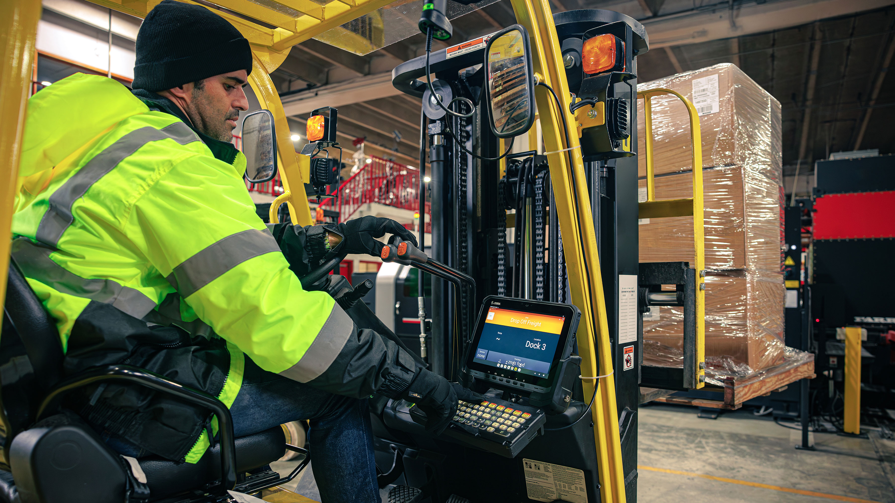 Warehouse worker operating a forklift and using a Zebra mounted tablet. Warehouse worker operating a forklift and using a Zebra mounted tablet.