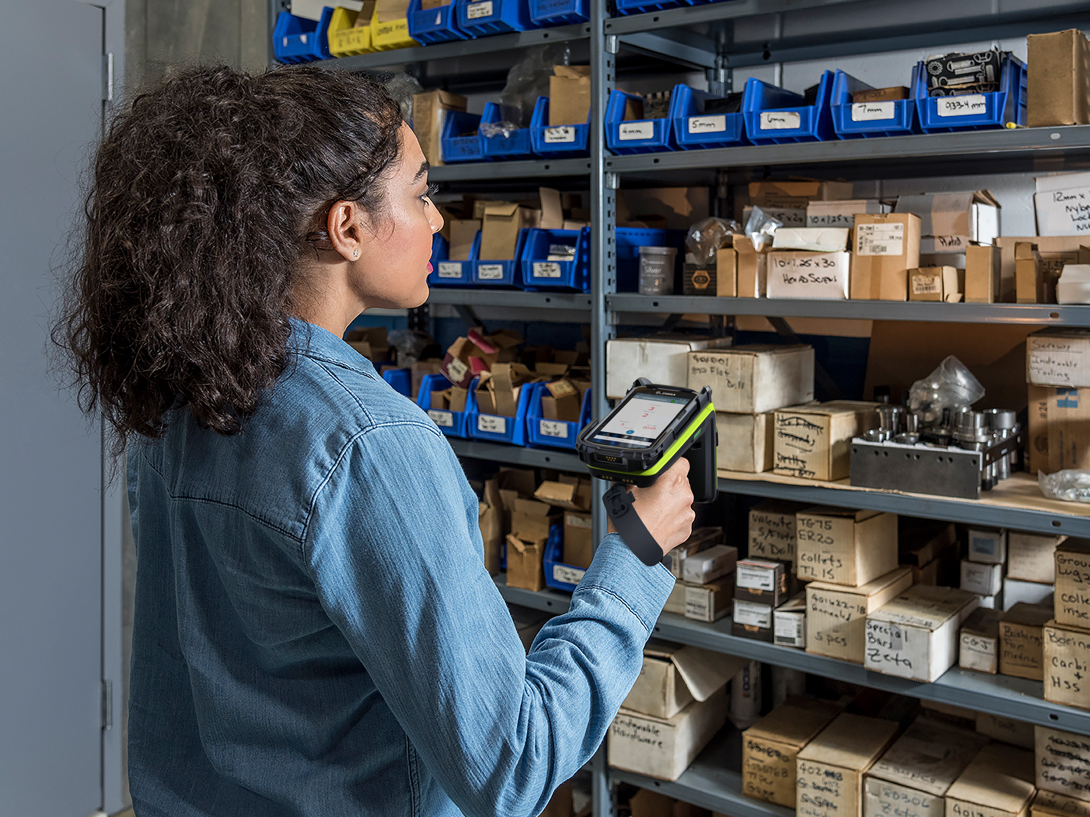 Warehouse worker scanning items on shelves using a Zebra Rugged Scanner Warehouse worker scanning items on shelves using a Zebra Rugged Scanner