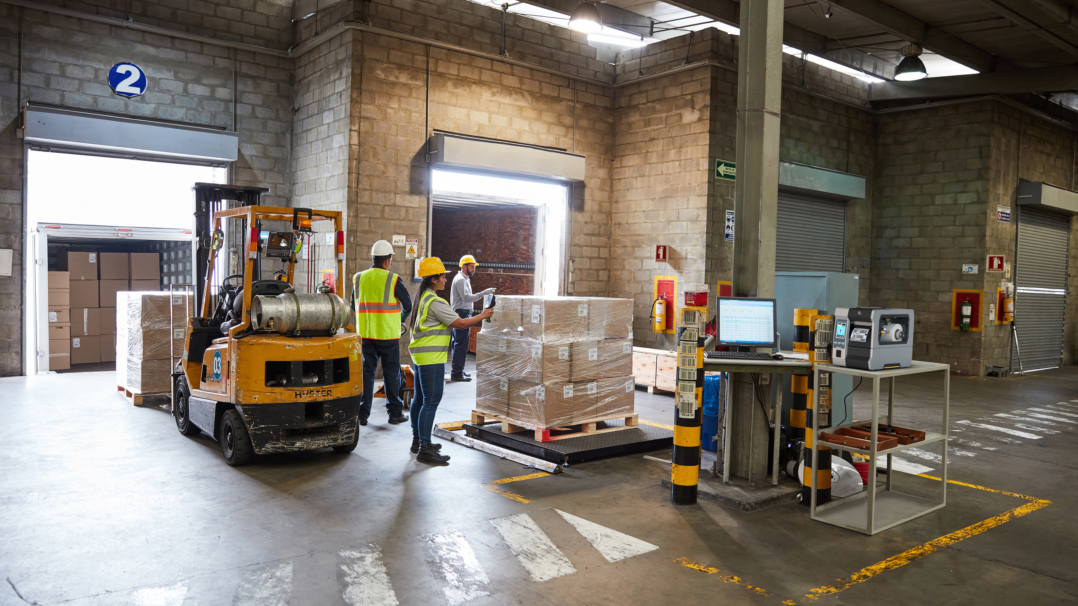 Workers using a forklift in a warehouse dock. Workers using a forklift in a warehouse dock.