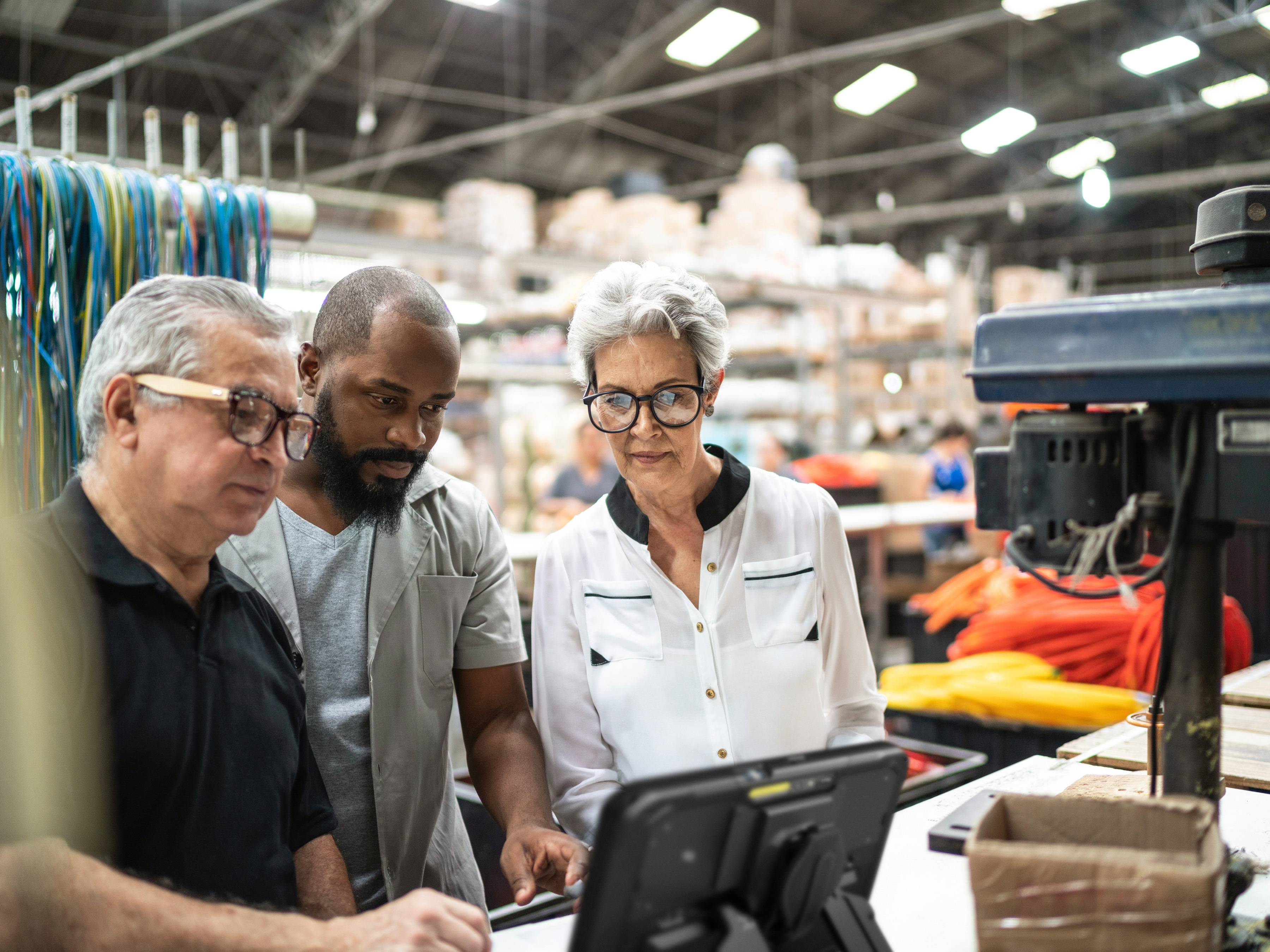 Three coworkers collaborating around a Zebra tablet inside of a factory setting. GettyImages-1196010583
