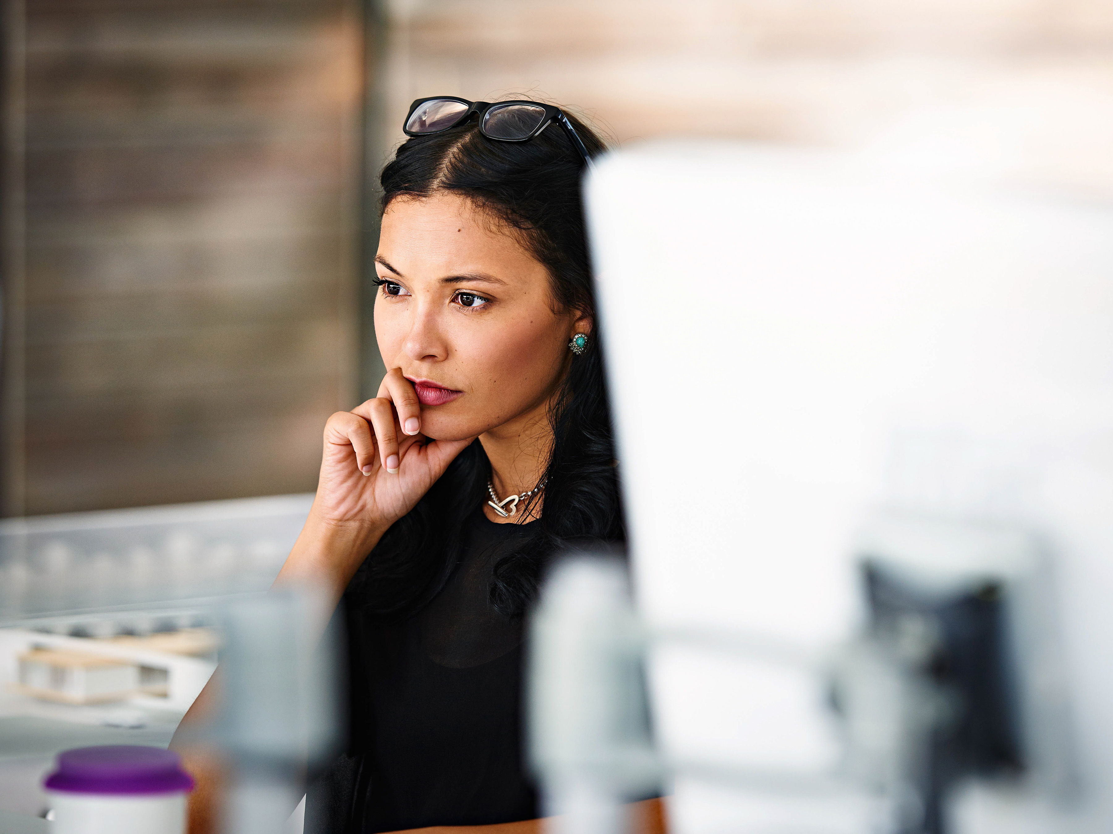 An employee is focusing while sitting at a desk in an office. An employee is focusing while sitting at a desk in an office.