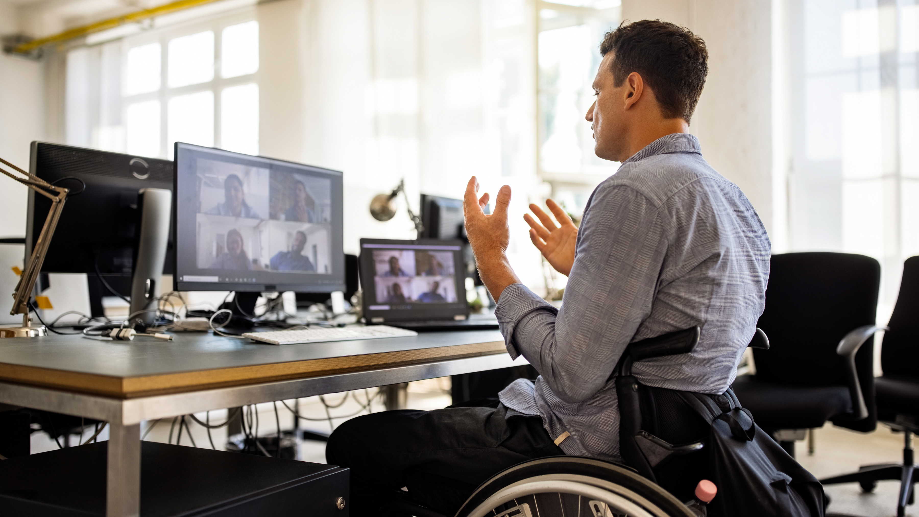 Wheelchair bound employee at an office workstation participating in a video conference call.  Wheelchair bound employee at an office workstation participating in a video conference call.