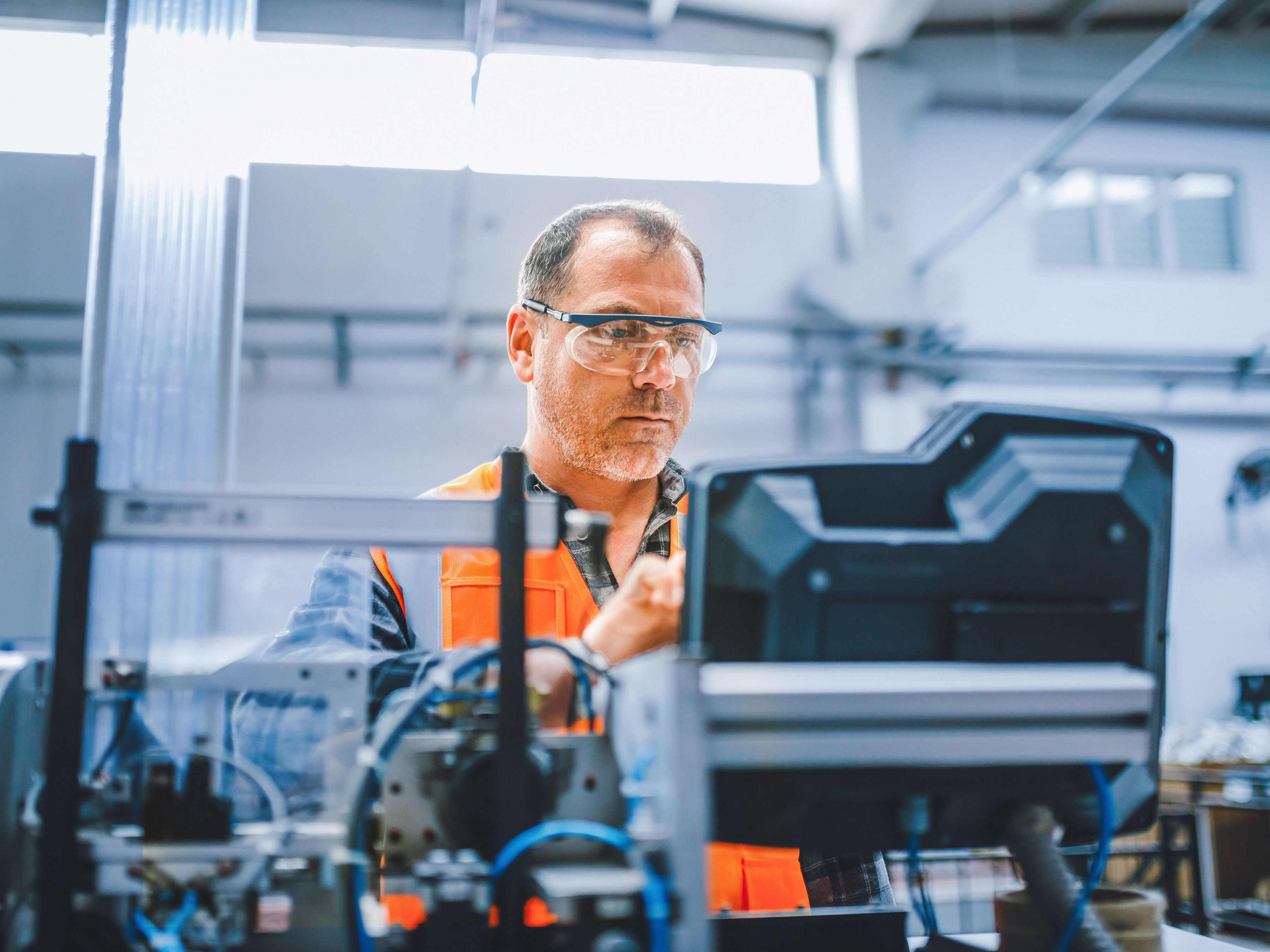 An industrial worker reviewing the controls on an equipment workstation inside of a factory. An industrial worker reviewing the controls on an equipment workstation inside of a factory.