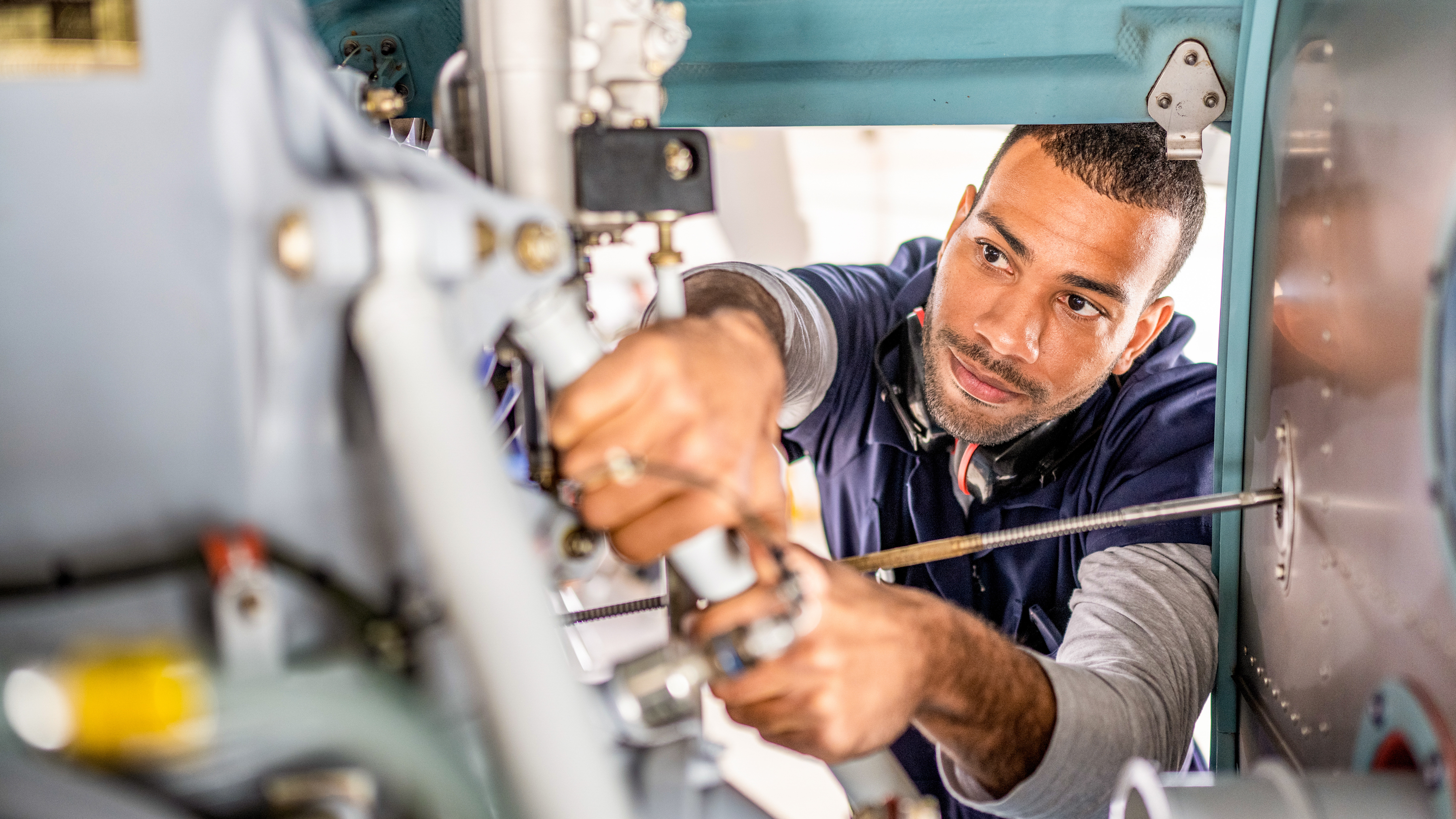 A mechanic is working on machinery, focusing intently on adjusting a component. A mechanic is working on machinery, focusing intently on adjusting a component.