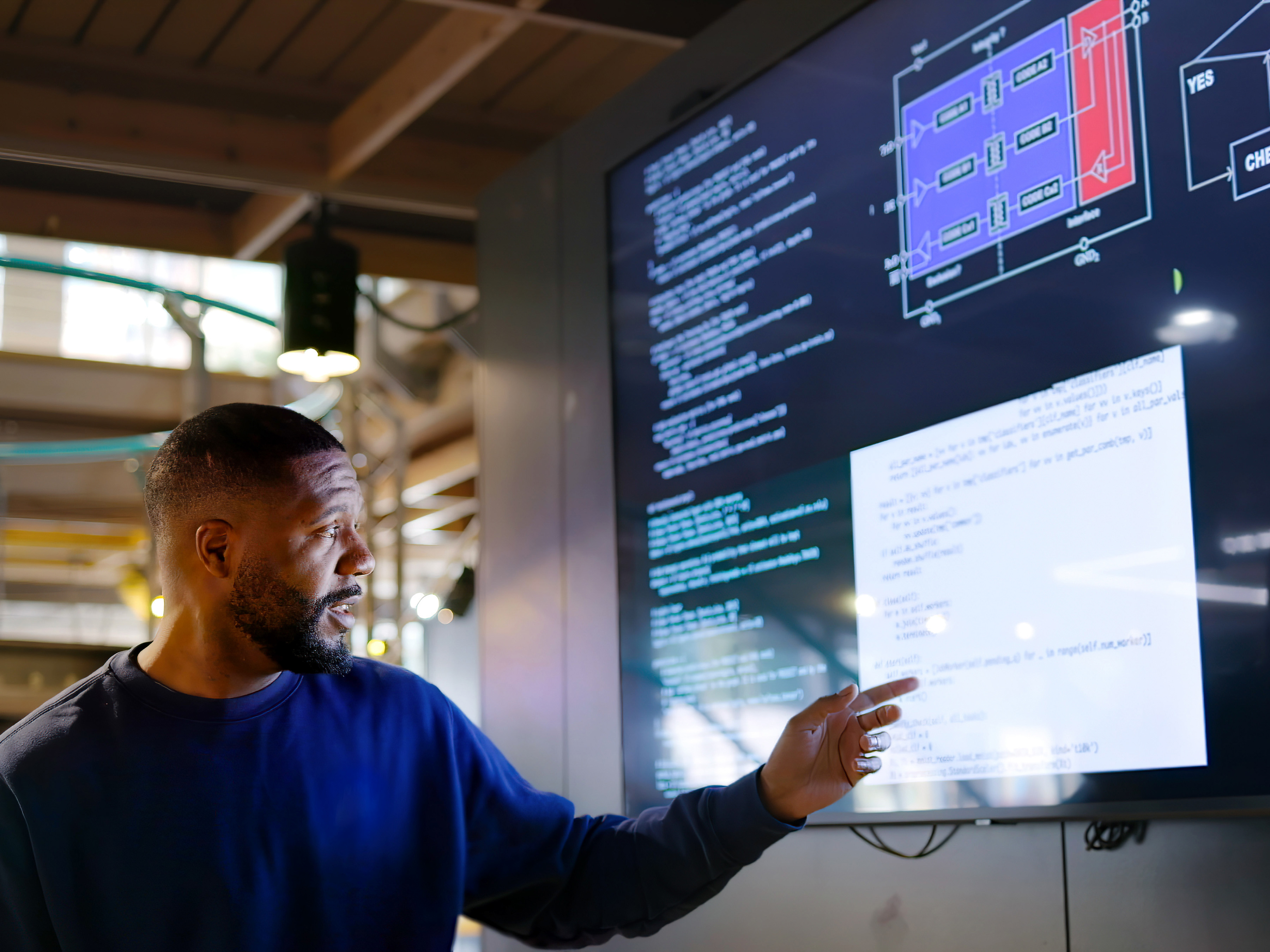 A person presenting code on a large monitor inside a modern office space.  A person presenting code on a large monitor inside a modern office space.