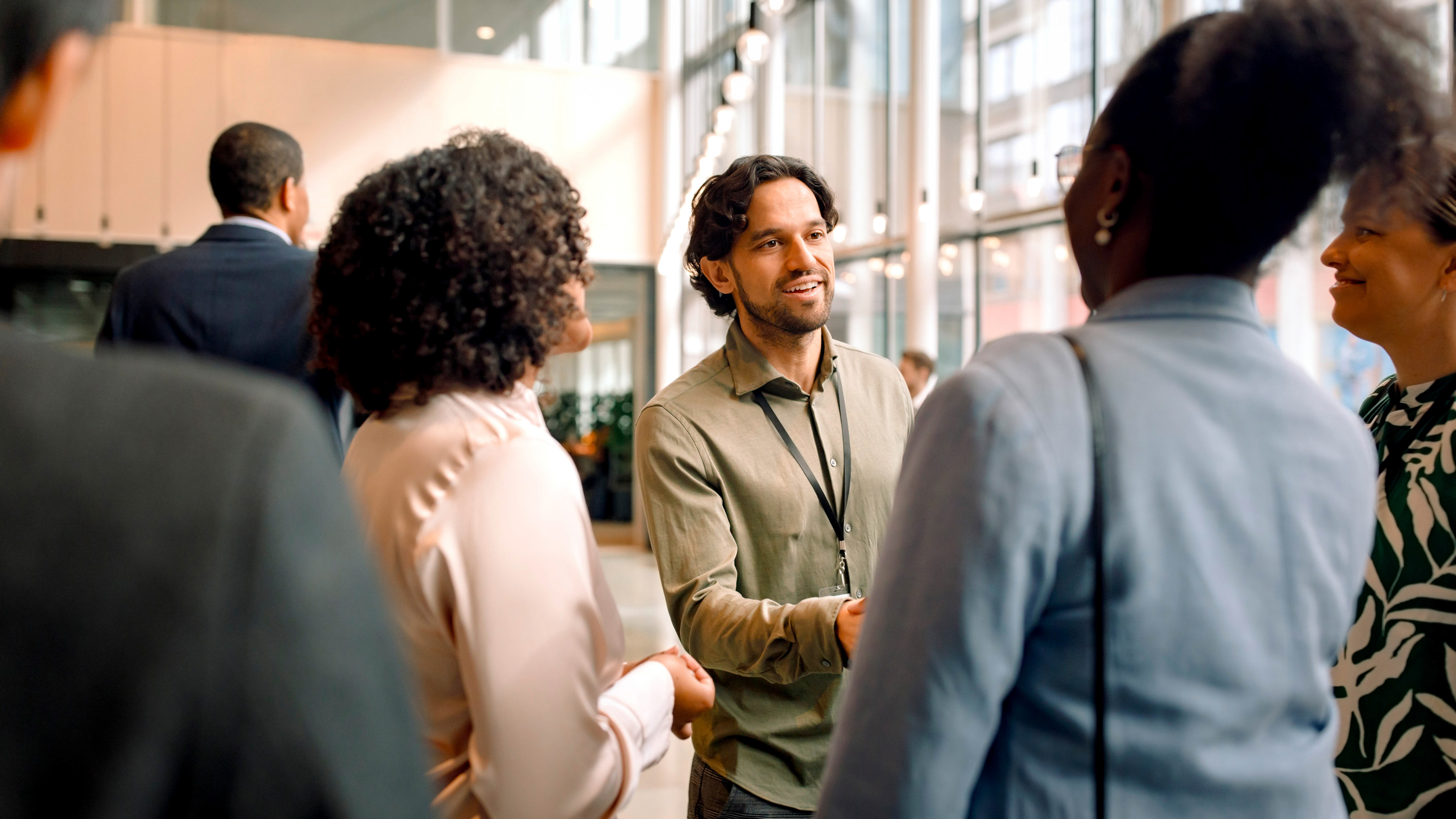 A group of professionals are meeting one another and exchanging handshakes at a conference center. A group of professionals are meeting one another and exchanging handshakes at a conference center.