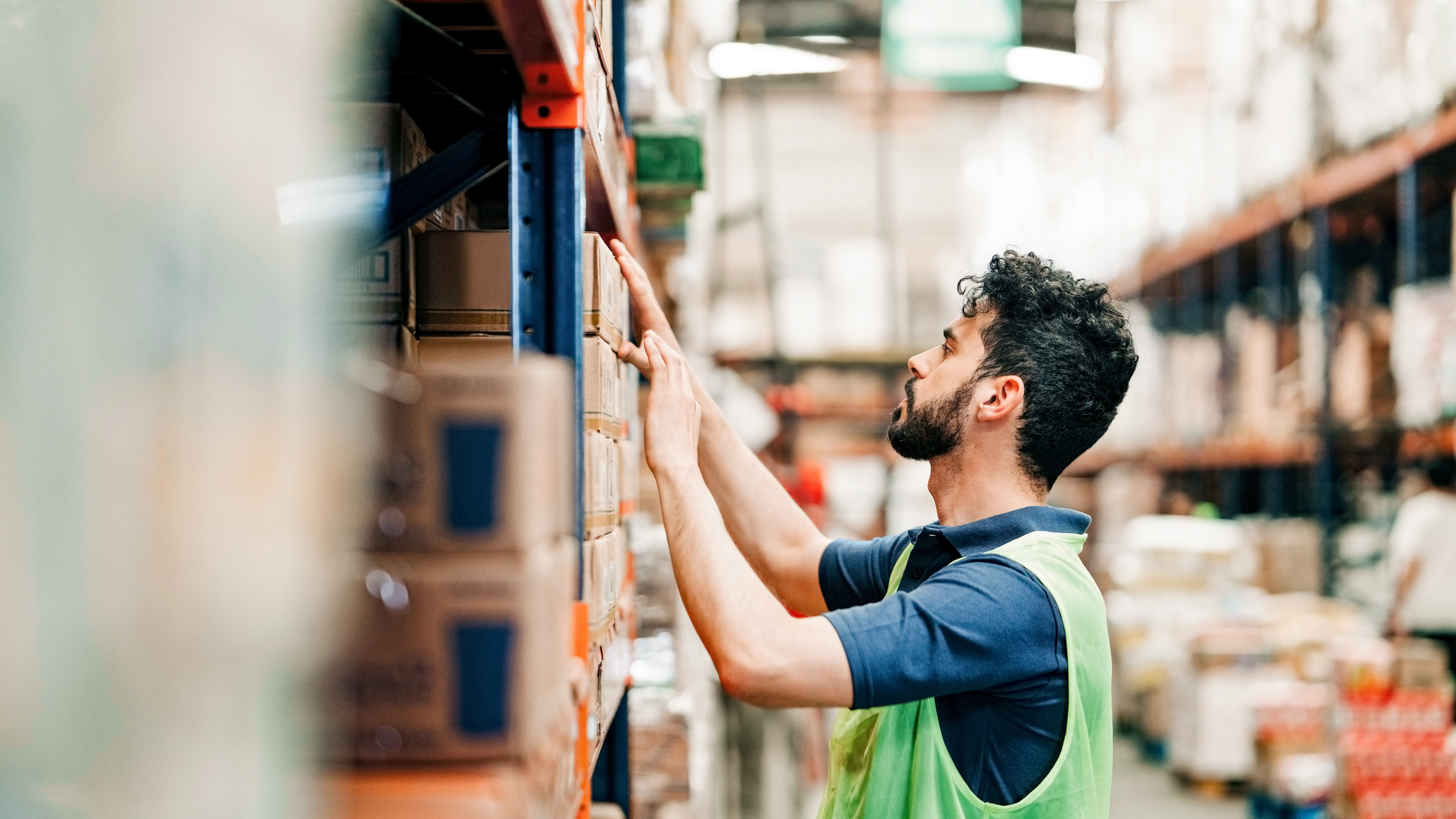 A worker is checking inventory on a shelf in a warehouse. A worker is checking inventory on a shelf in a warehouse.
