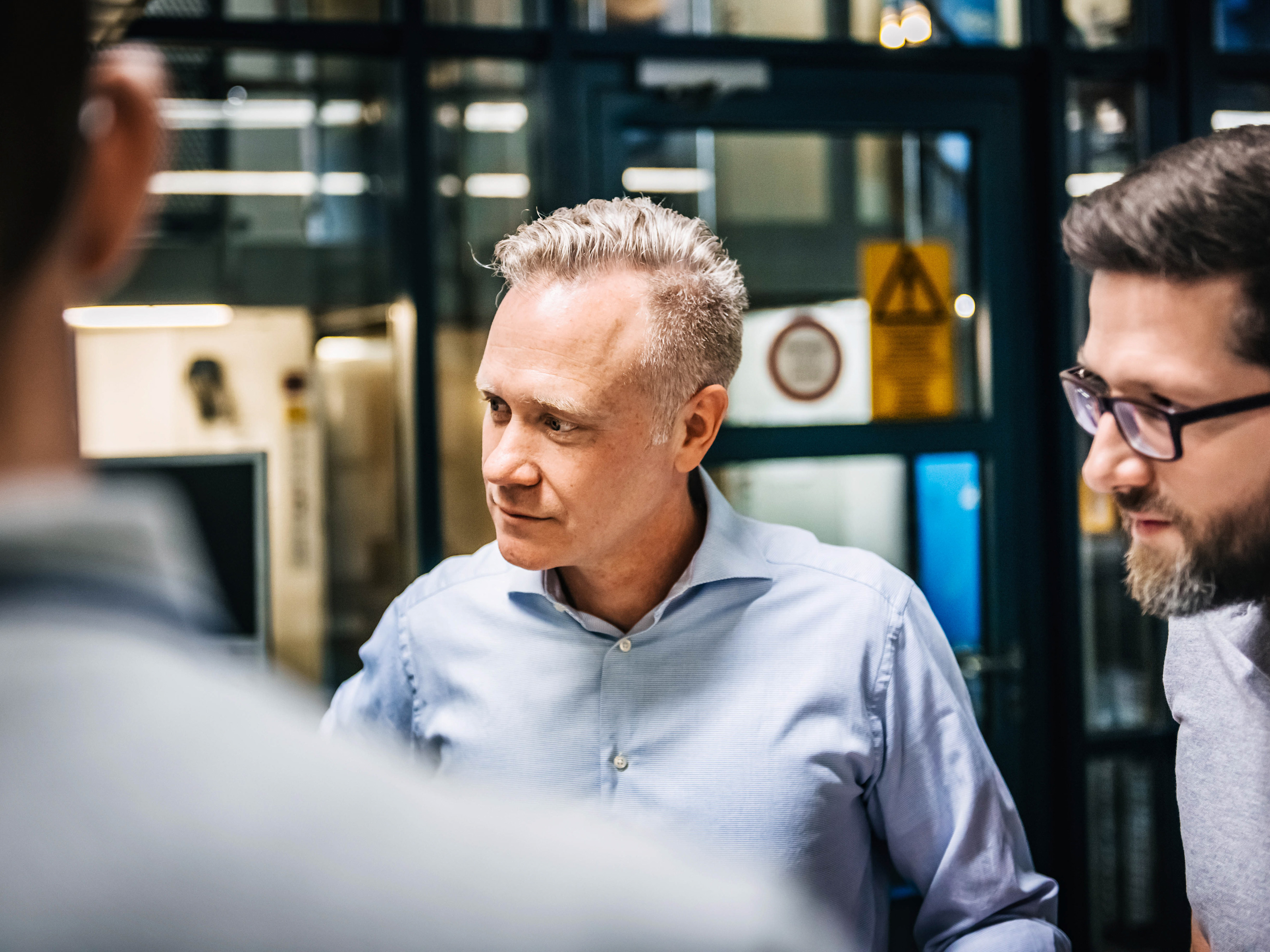 A group of employees are attentively listening during a manufacturing meeting. A group of employees are attentively listening during a manufacturing meeting.