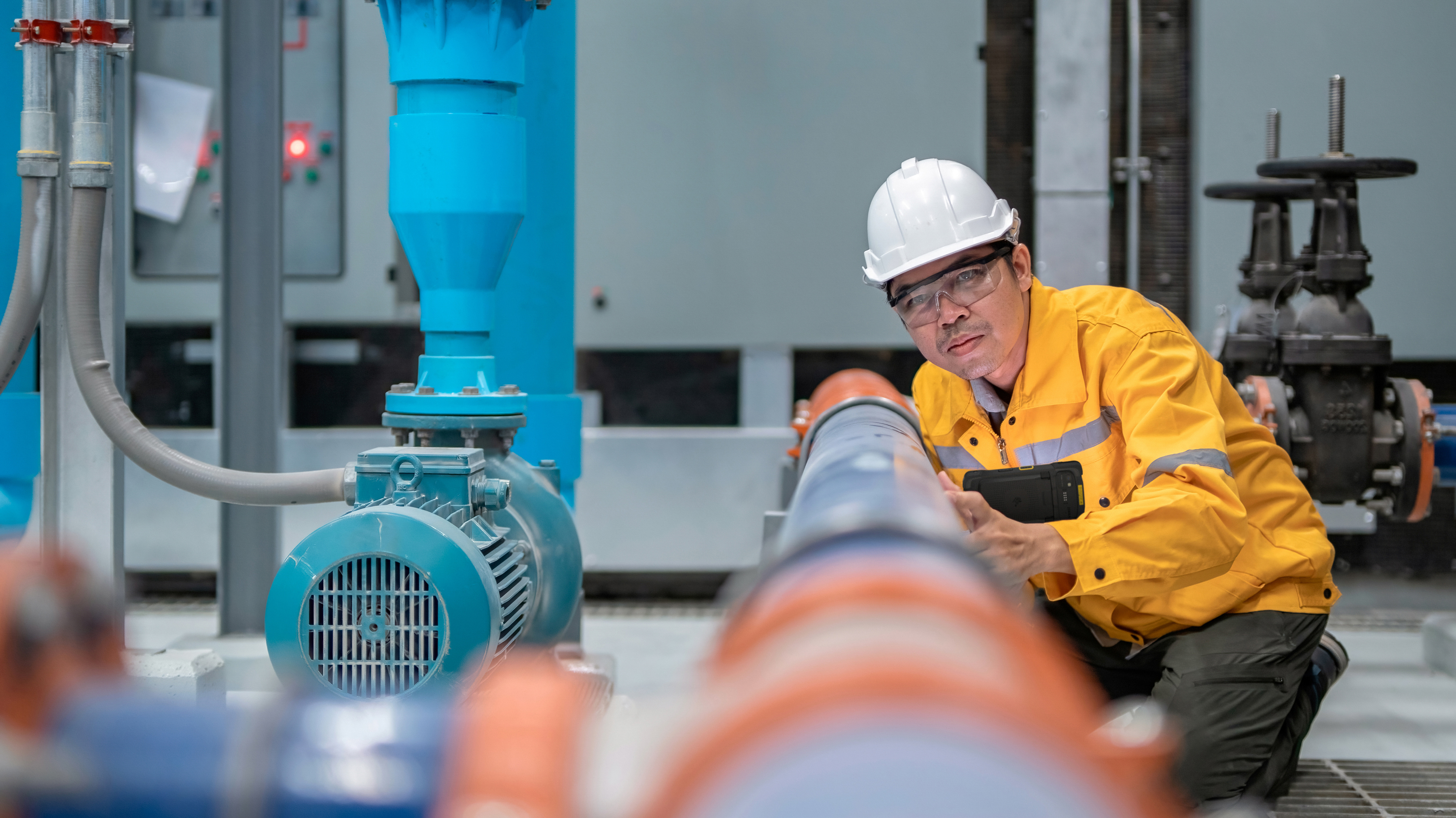 An engineer using a handheld mobile computer to inspect a water pump. An engineer using a handheld mobile computer to inspect a water pump.