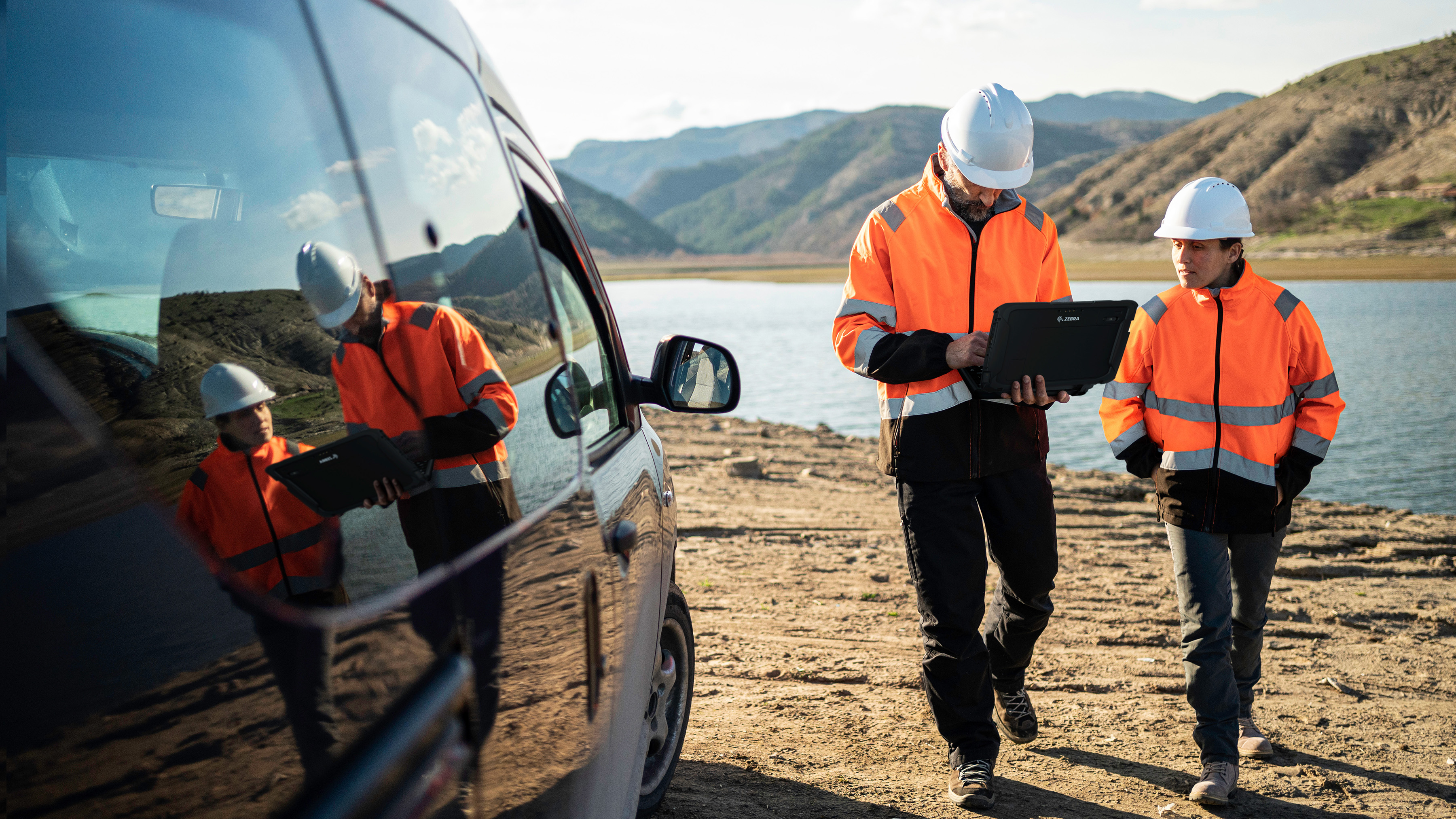 Engineer walking outdoors near water with a Zebra tablet.  Engineer walking outdoors near water with a Zebra tablet.