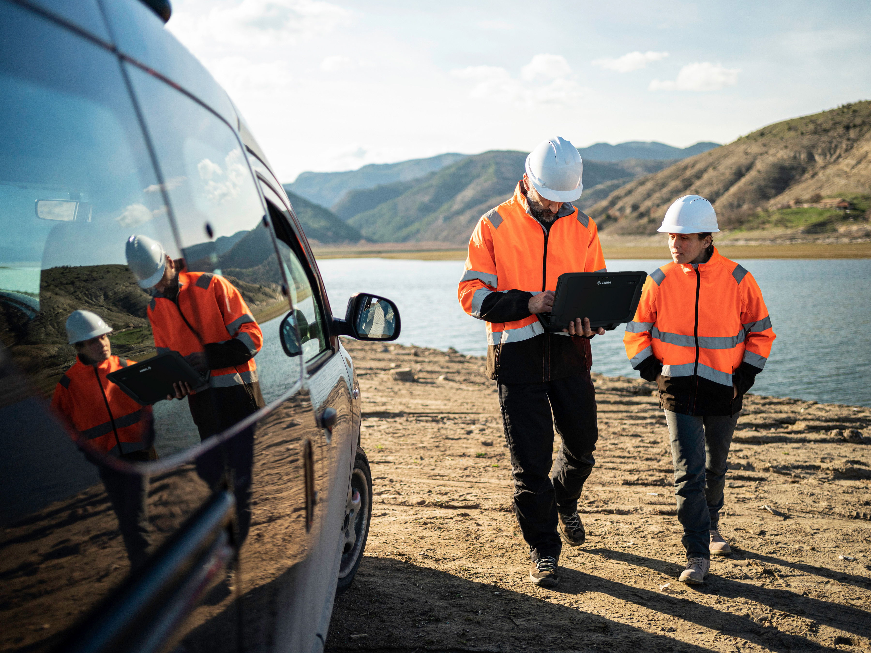Engineer walking outdoors near water with a Zebra tablet.  Engineer walking outdoors near water with a Zebra tablet.