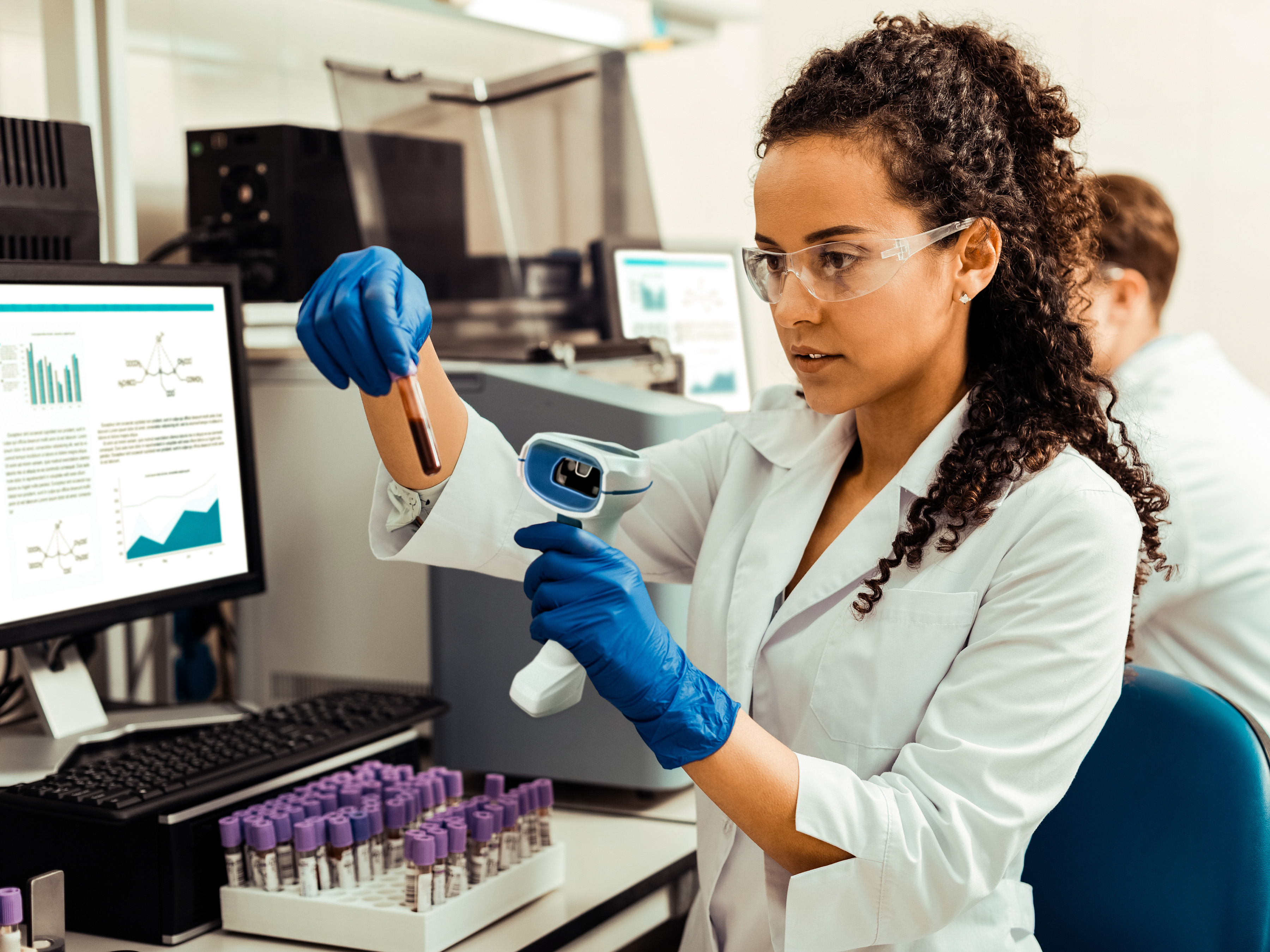 A medical professional uses a Zebra handheld barcode scanner to scan a label on a blood sample. A medical professional uses a Zebra handheld barcode scanner to scan a label on a blood sample.