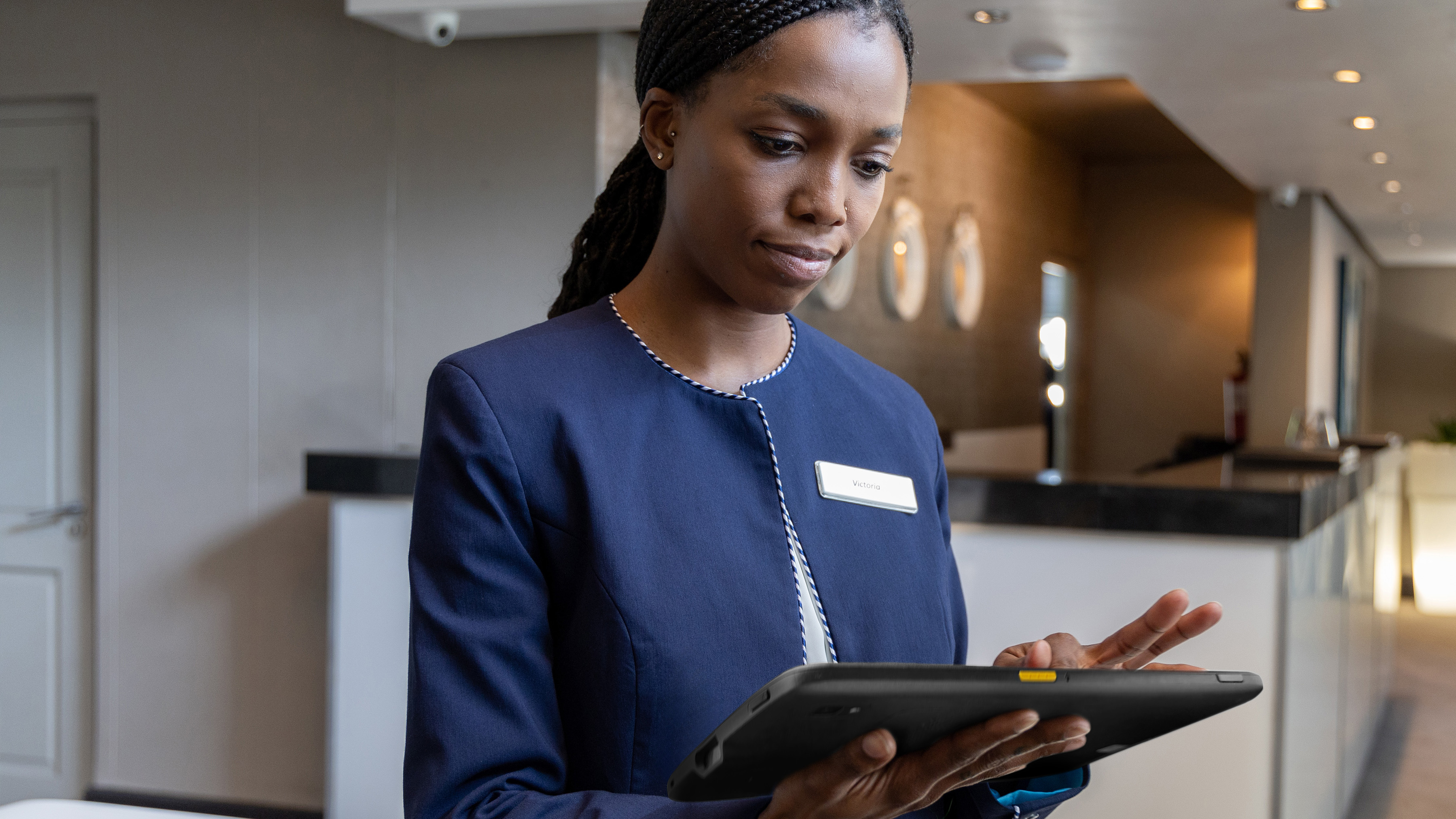Hospitality worker using a Zebra tablet at a hotel event. Hospitality worker using a Zebra tablet at a hotel event.