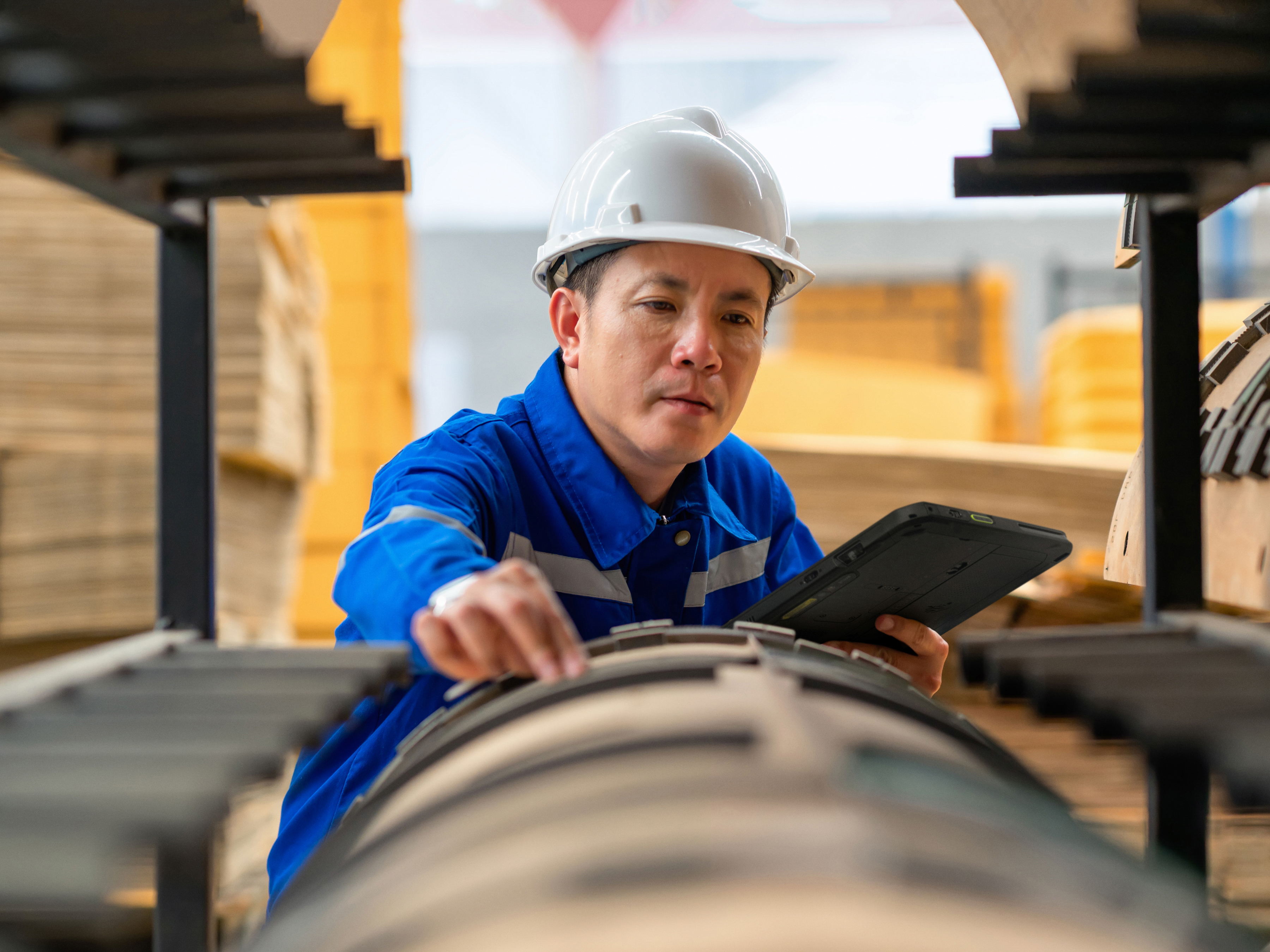 An engineer reviewing a tablet during a quality control inspection inside of a manufacturing plant. An engineer reviewing a tablet during a quality control inspection inside of a manufacturing plant.