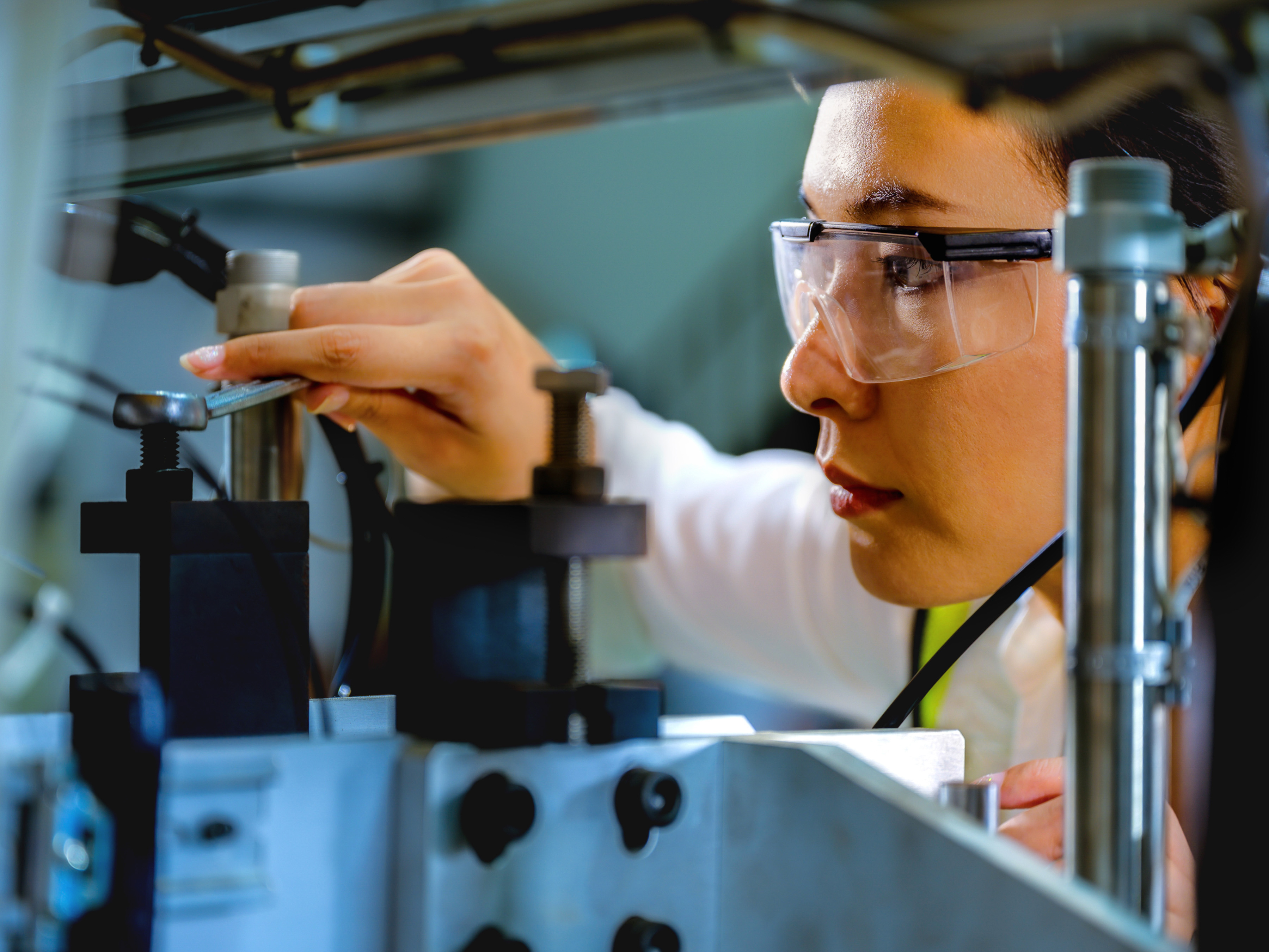 A technician uses a wrench to adjust a bolt on industrial machinery. A technician uses a wrench to adjust a bolt on industrial machinery.