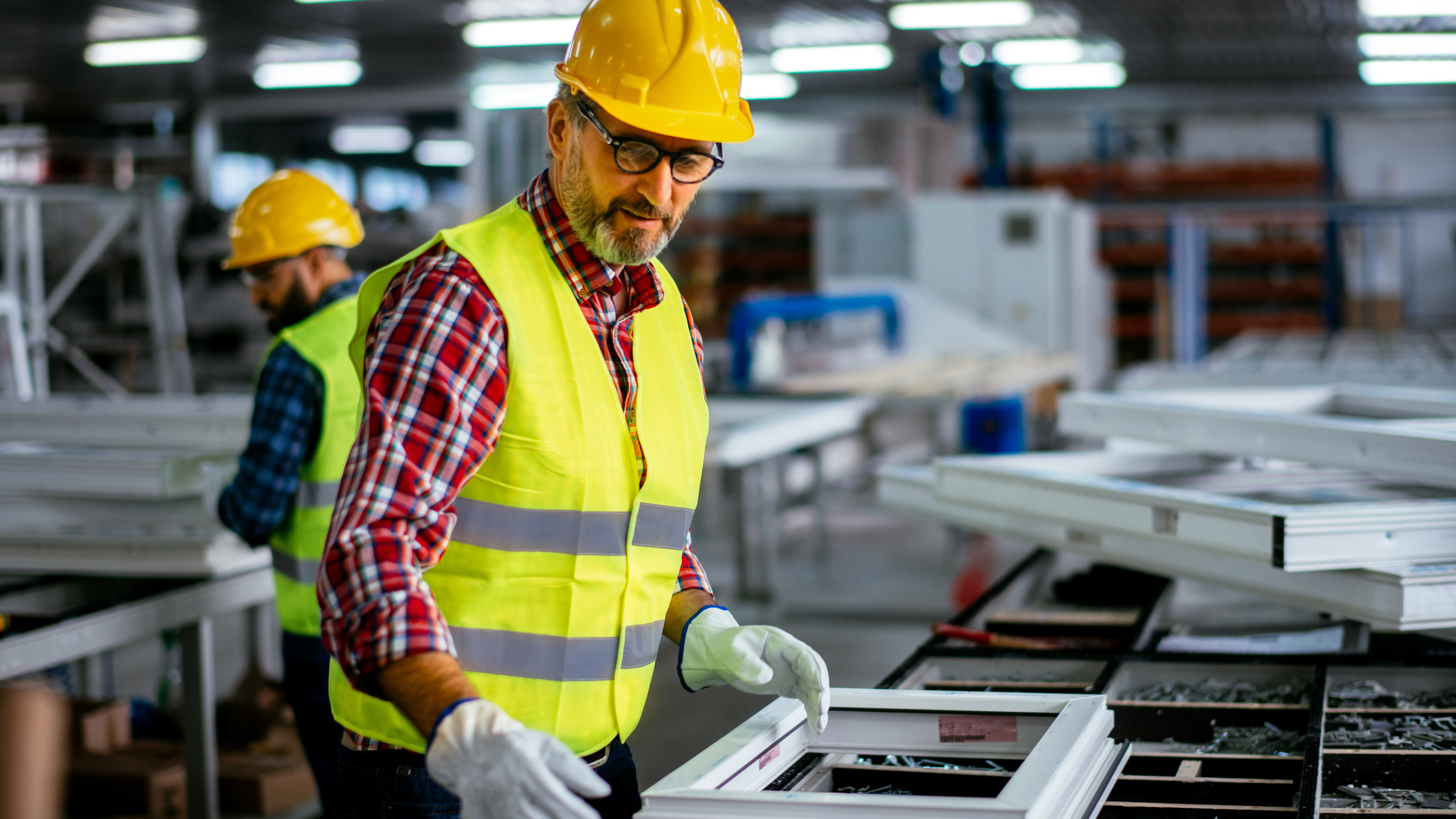 A worker assembling windows inside of a manufacturing plant. A worker assembling windows inside of a manufacturing plant.