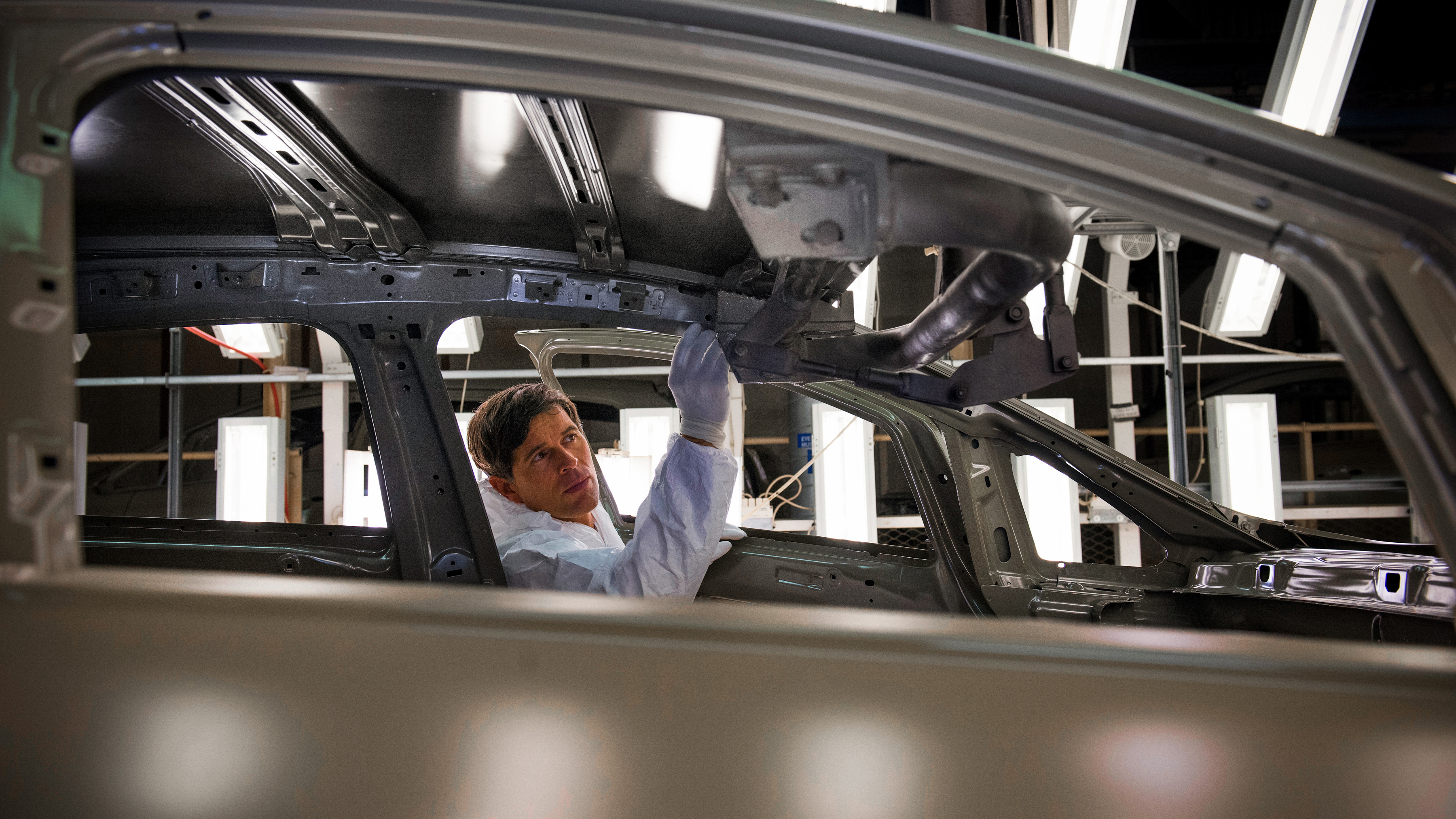 Manufacturing worker inspecting a car on the production line.  Manufacturing worker inspecting a car on the production line.