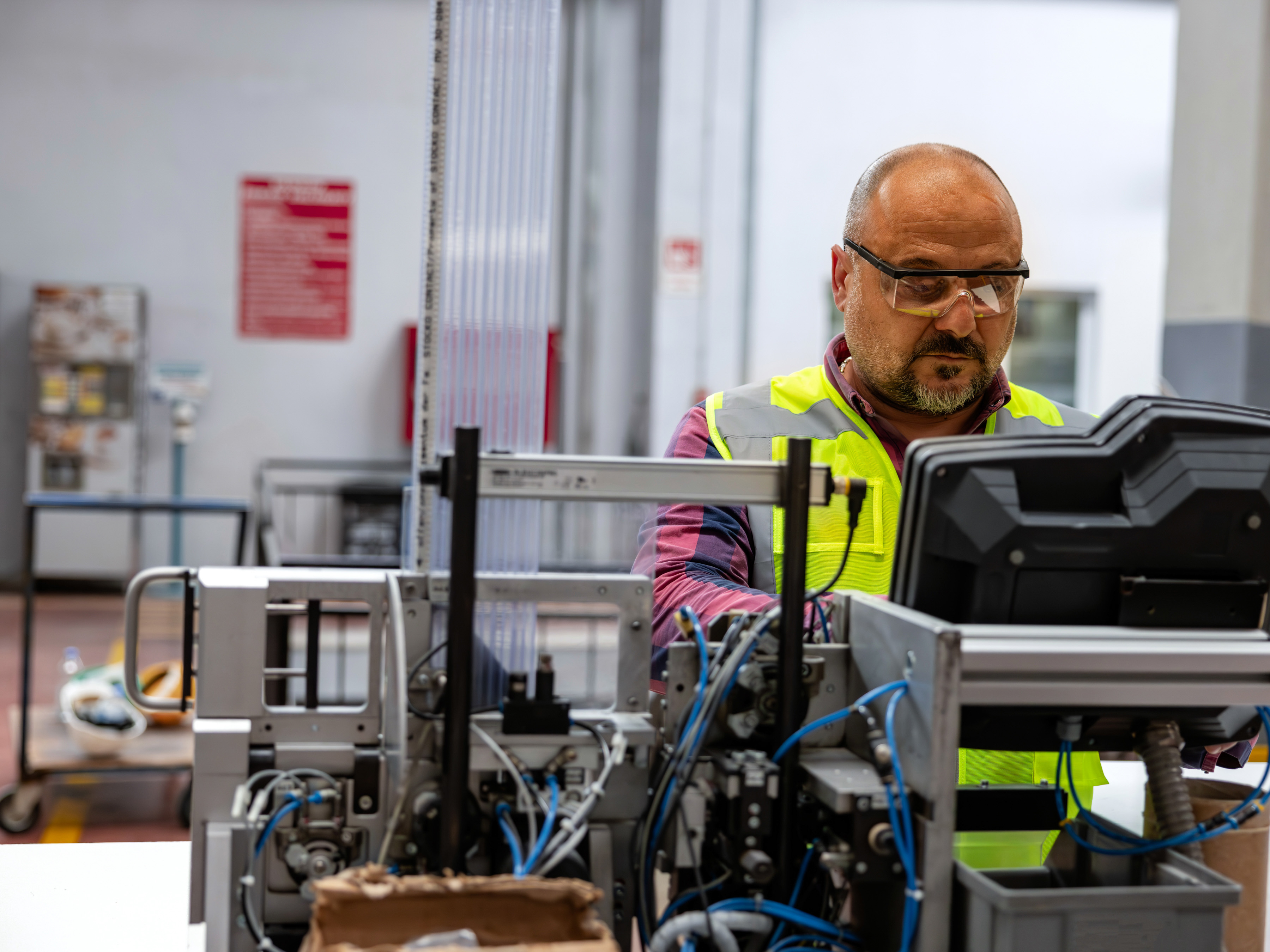 A worker looks at a screen while managing machinery in a factory. A worker looks at a screen while managing machinery in a factory.