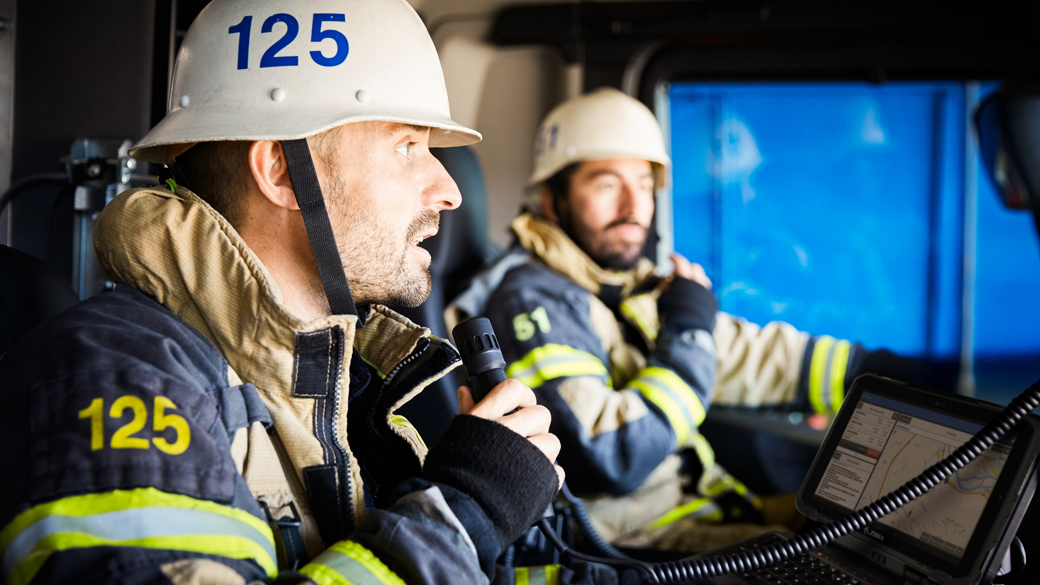 Two firefighters reviewing a Zebra ugged tablet inside of a firetruck. Two firefighters reviewing a Zebra ugged tablet inside of a firetruck.