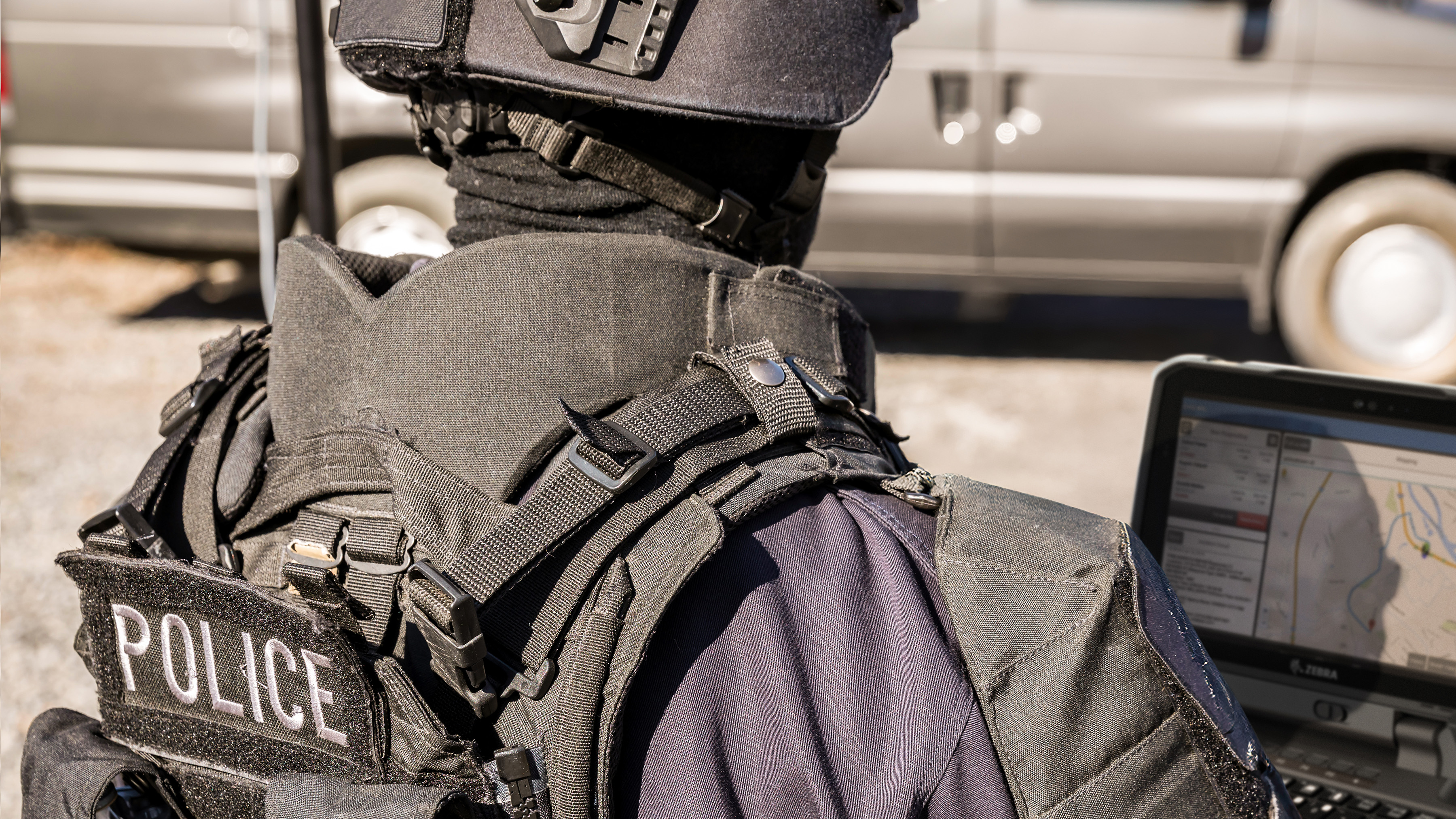 A tactical police officer using a Zebra rugged handheld tablet during a field operation. A tactical police officer using a Zebra rugged handheld tablet during a field operation.