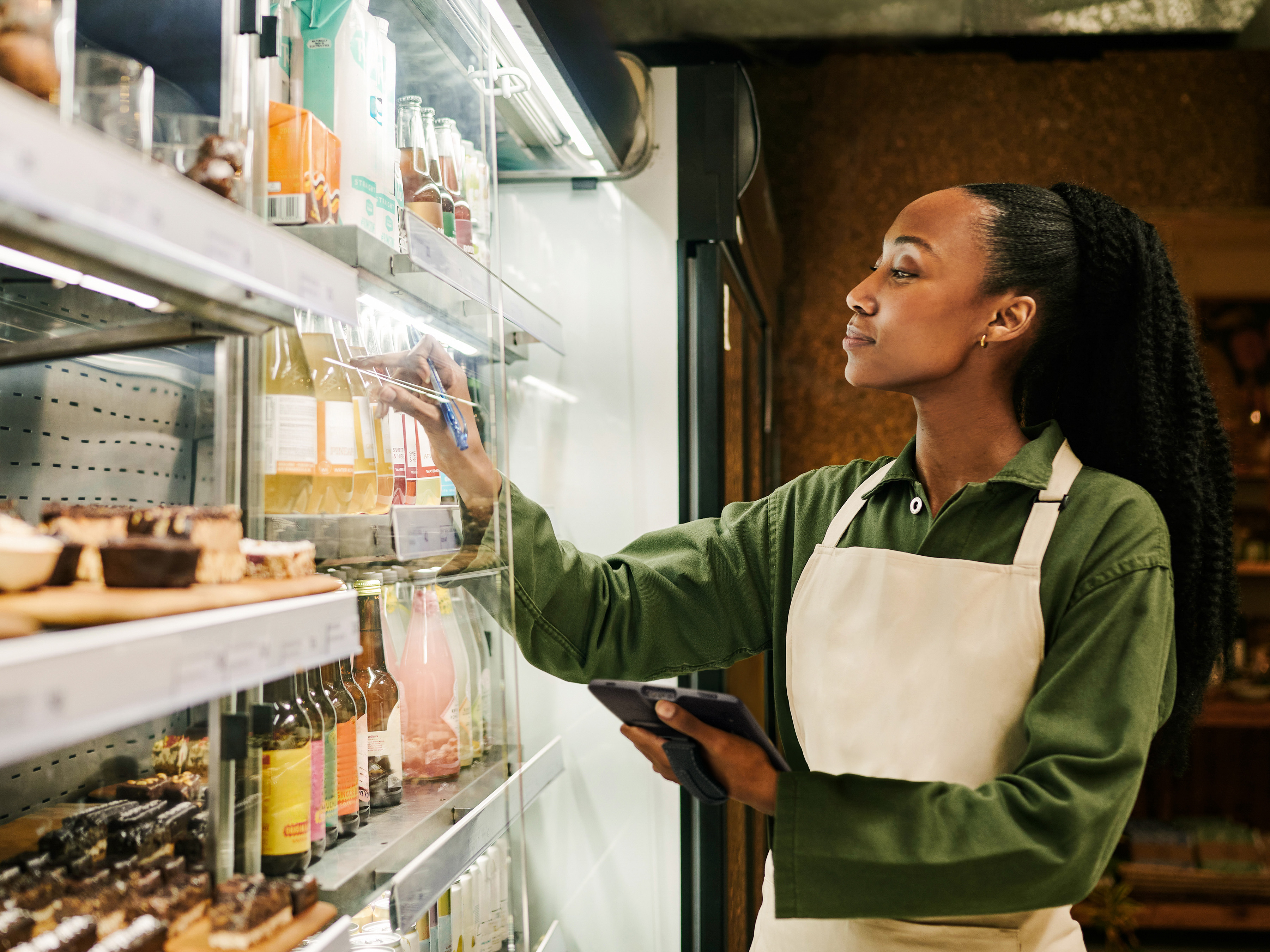 A front-of-house employee checking juice stock inside of a grocery store. A front-of-house employee checking juice stock inside of a grocery store.