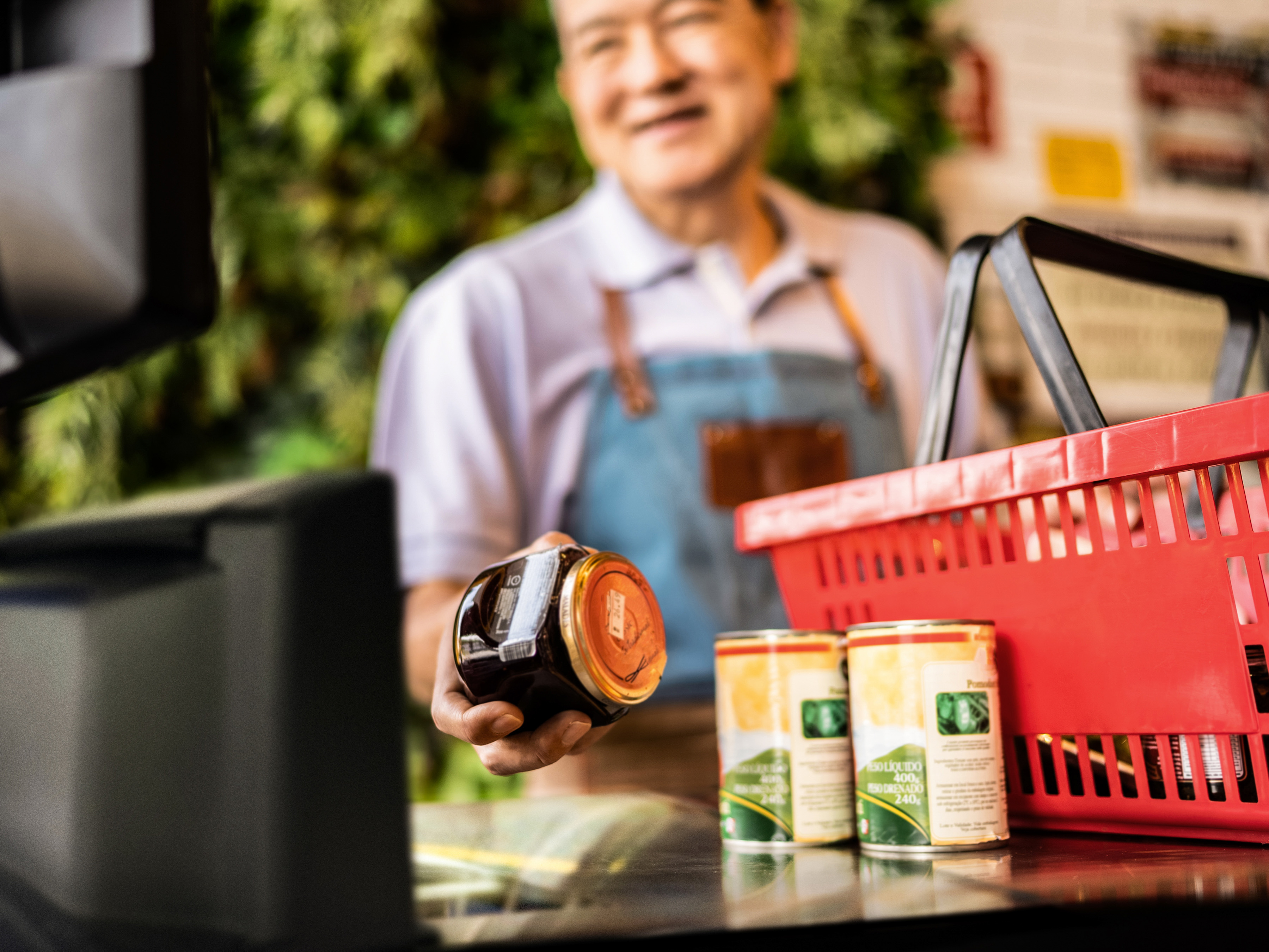 A front-of-house employee scanning a jar with a fixed mount scanner at a grocery store checkout. A front-of-house employee scanning a jar with a fixed mount scanner at a grocery store checkout.