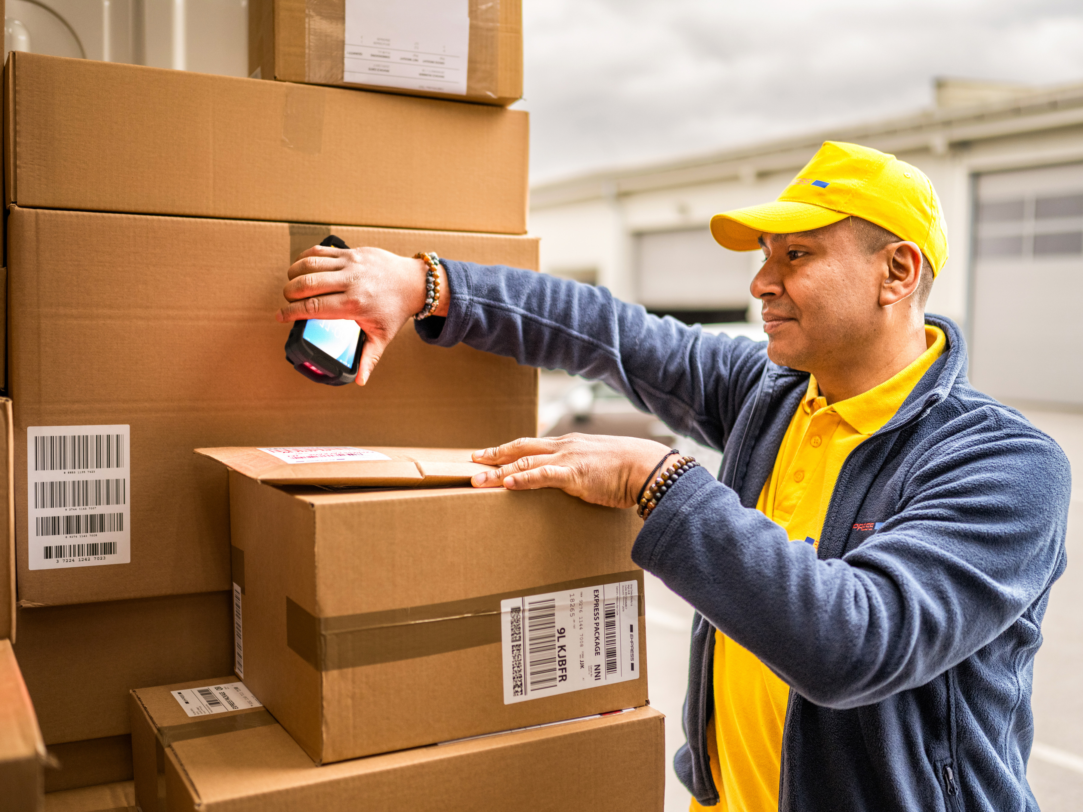 A transportation and logistics worker using a handheld mobile computer to scan packages inside the back of a delivery truck. A transportation and logistics worker using a handheld mobile computer to scan packages inside the back of a delivery truck.